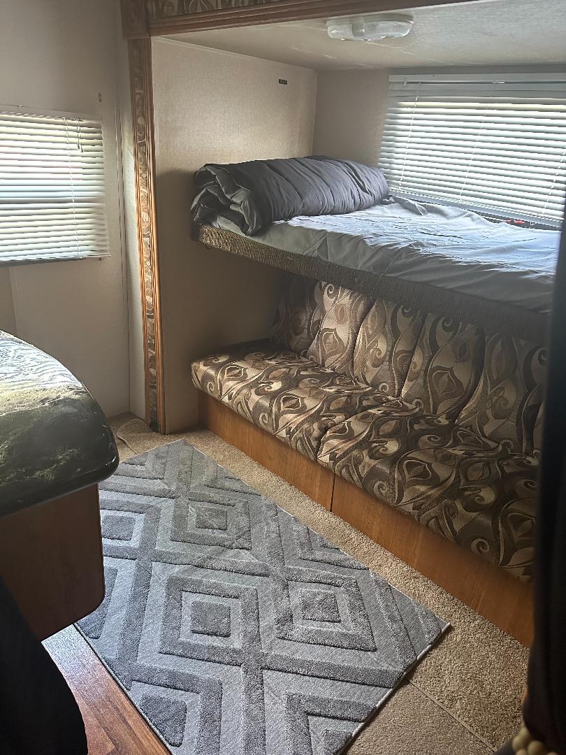 Explore this RV rental's functional interior: bunk beds, a patterned sofa, and rug create a compact living space.. Forest River Wildwood 2010