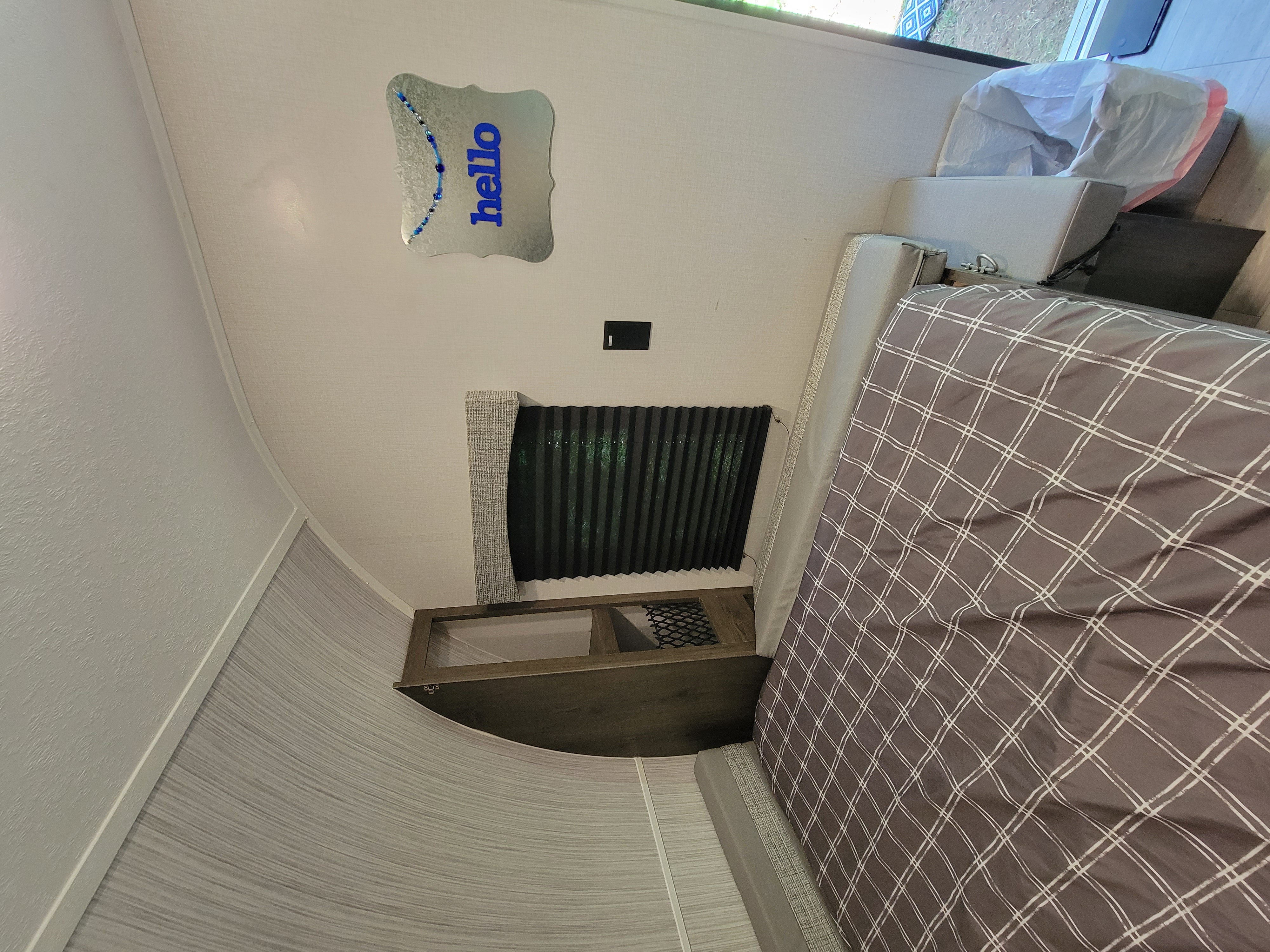 This RV rental's cozy bedroom features a brown plaid bed, pleated window blinds, built-in storage, and unique "hello" wall decor.. Clipper Ultra Lite 2022
