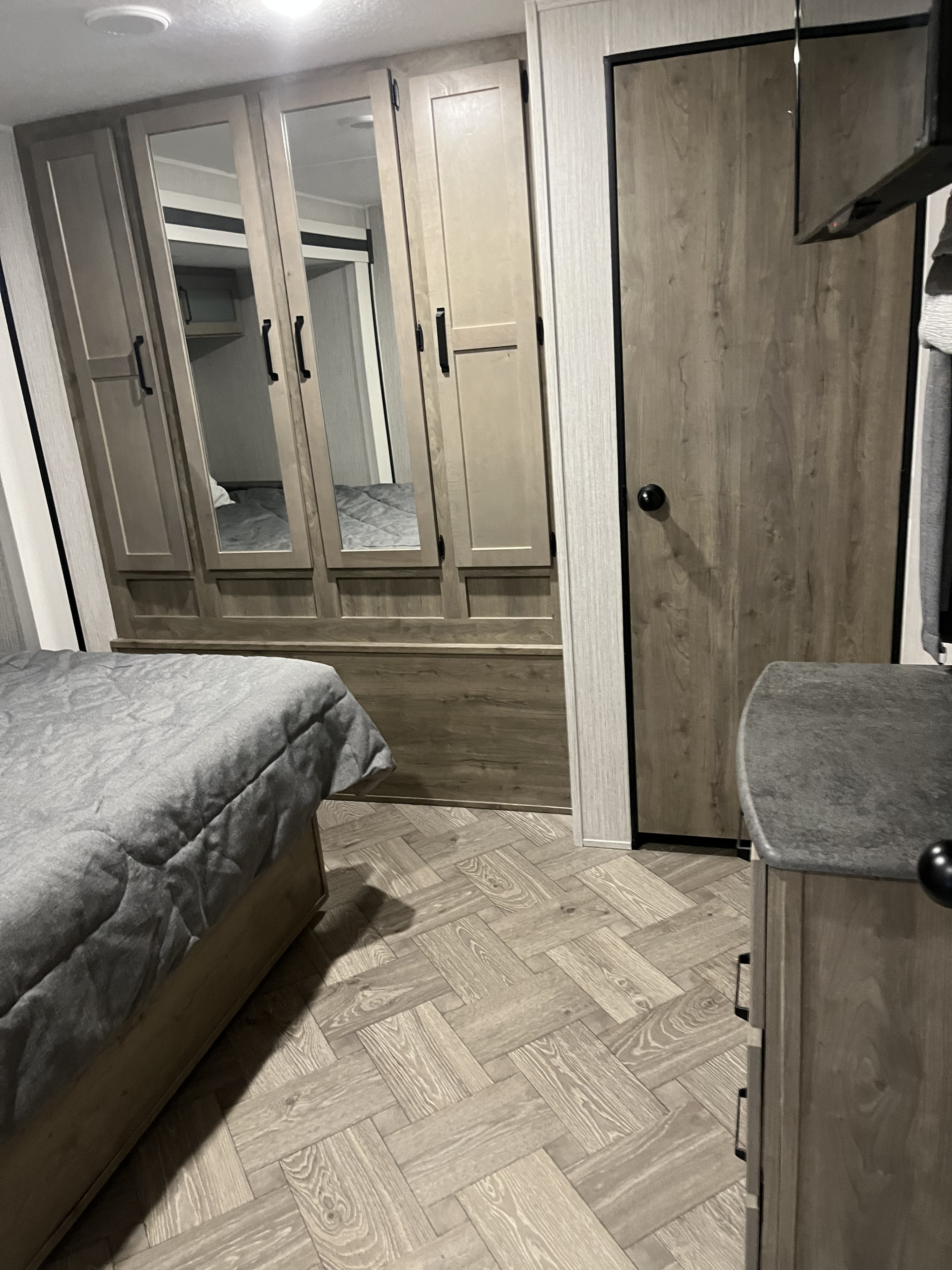 Experience comfort in this RV rental bedroom, featuring a gray bed, ample wardrobe, and stylish wood-look floor.. Forest River Palomino Puma 2021