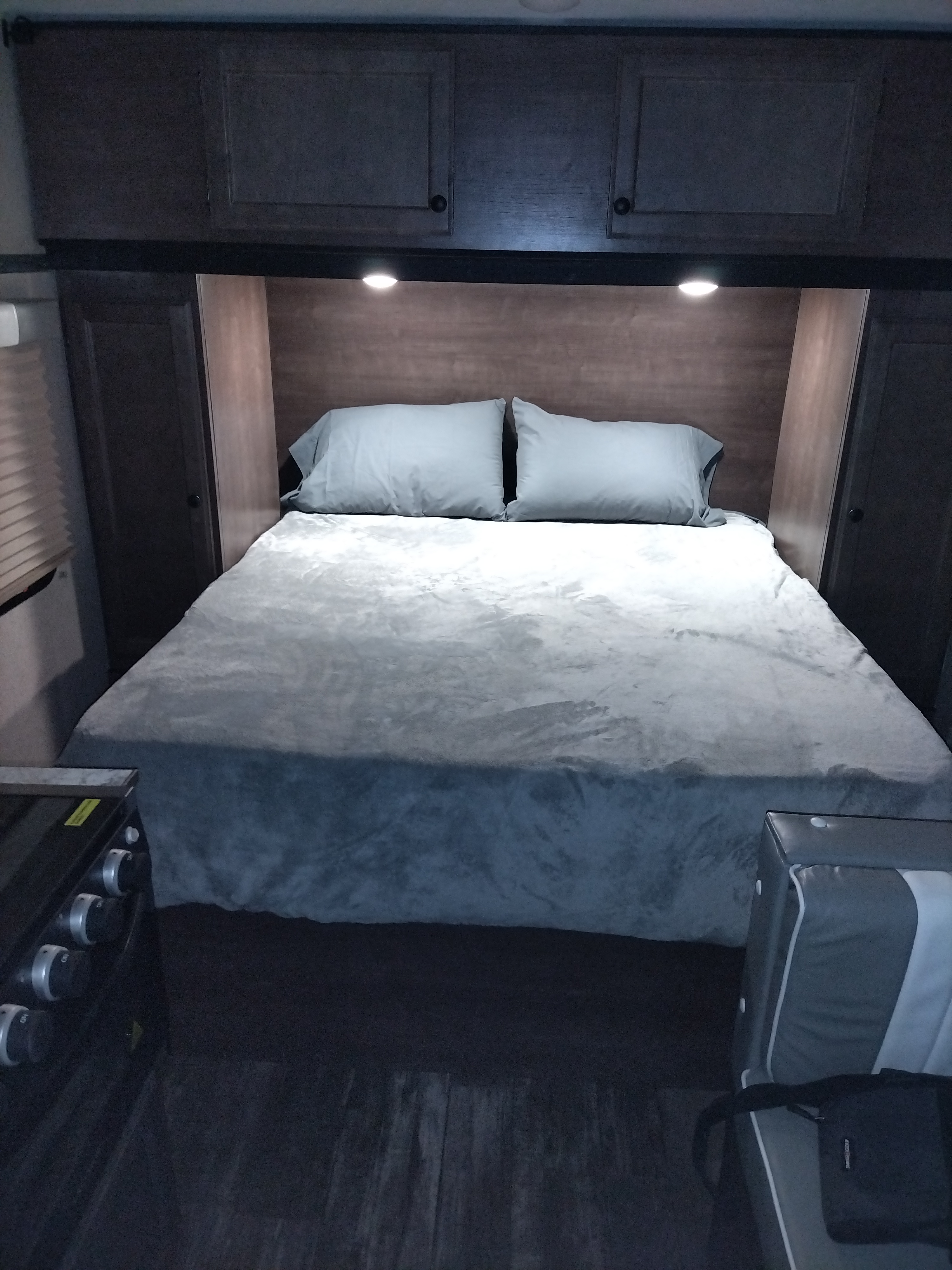 RV rental interior showing a compact bedroom with a bed, overhead cabinets, and built-in amenities for comfortable travel.. Sunset Park RV Sun Lite 2023
