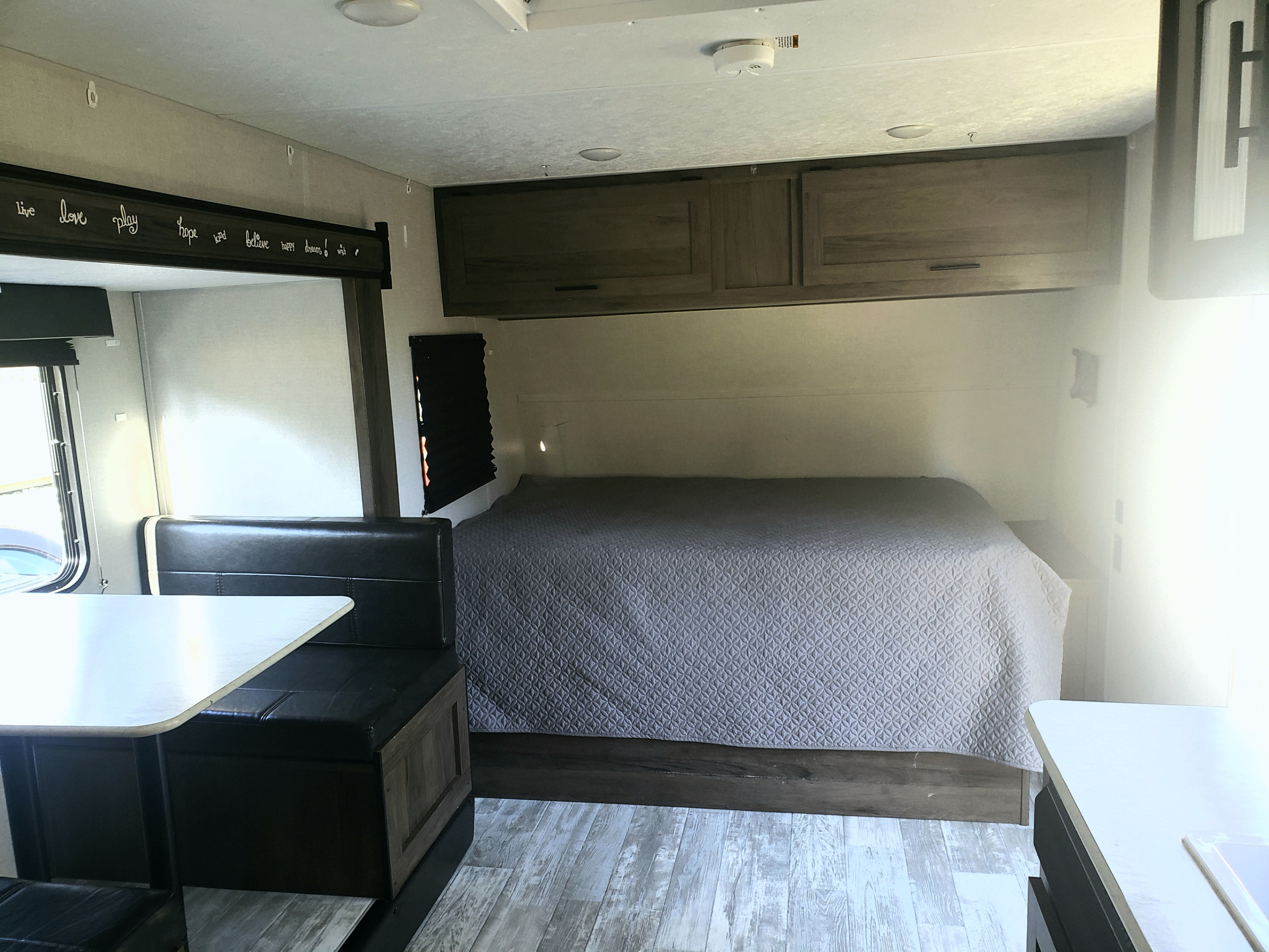 Inside this RV rental: a quilted bed, dinette seating, overhead cabinets, and light wood flooring.. Prime time Rv Avenger Lt 17 BHS 2021