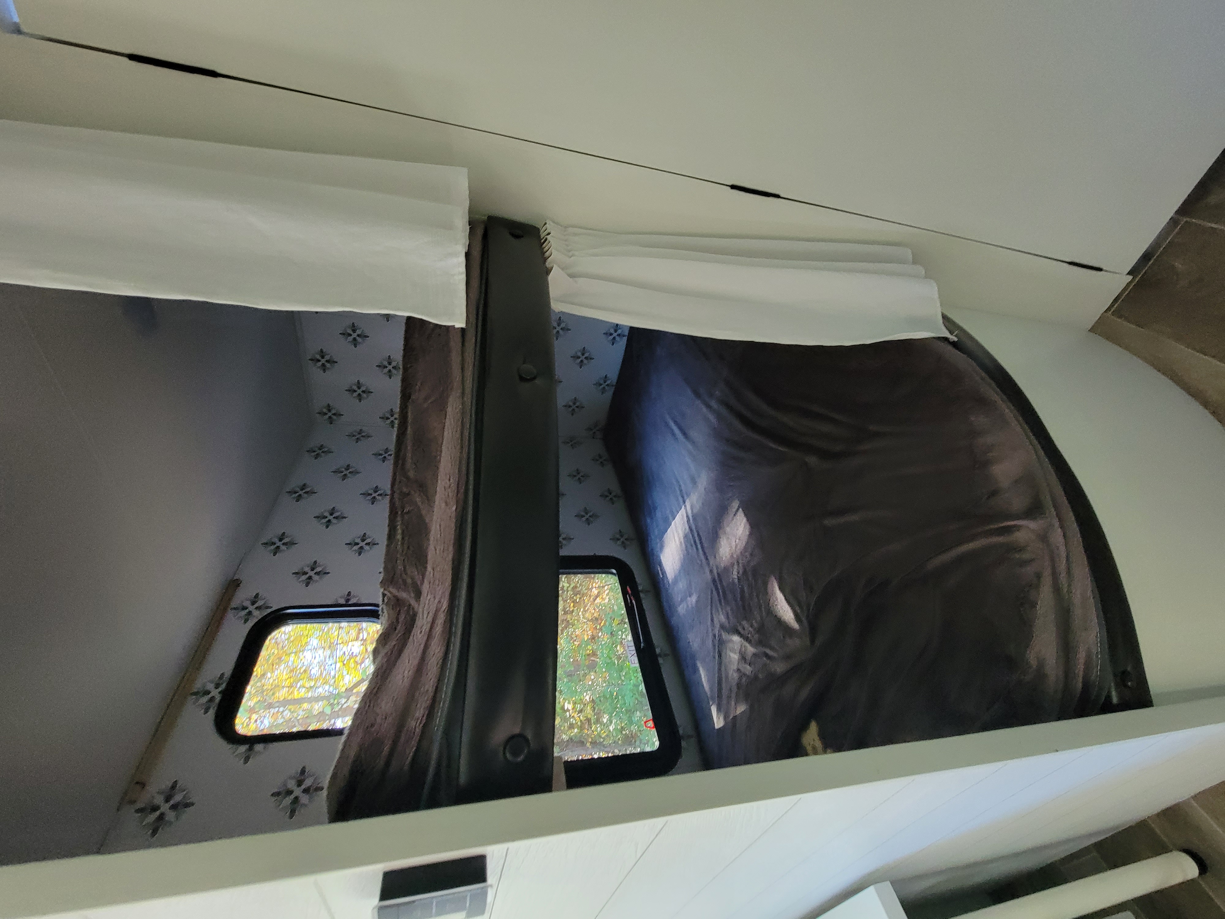 Upper bunk sleeping area in an RV rental, featuring patterned walls, windows, and white blinds.. Jayco Jay Flight SLX 2021