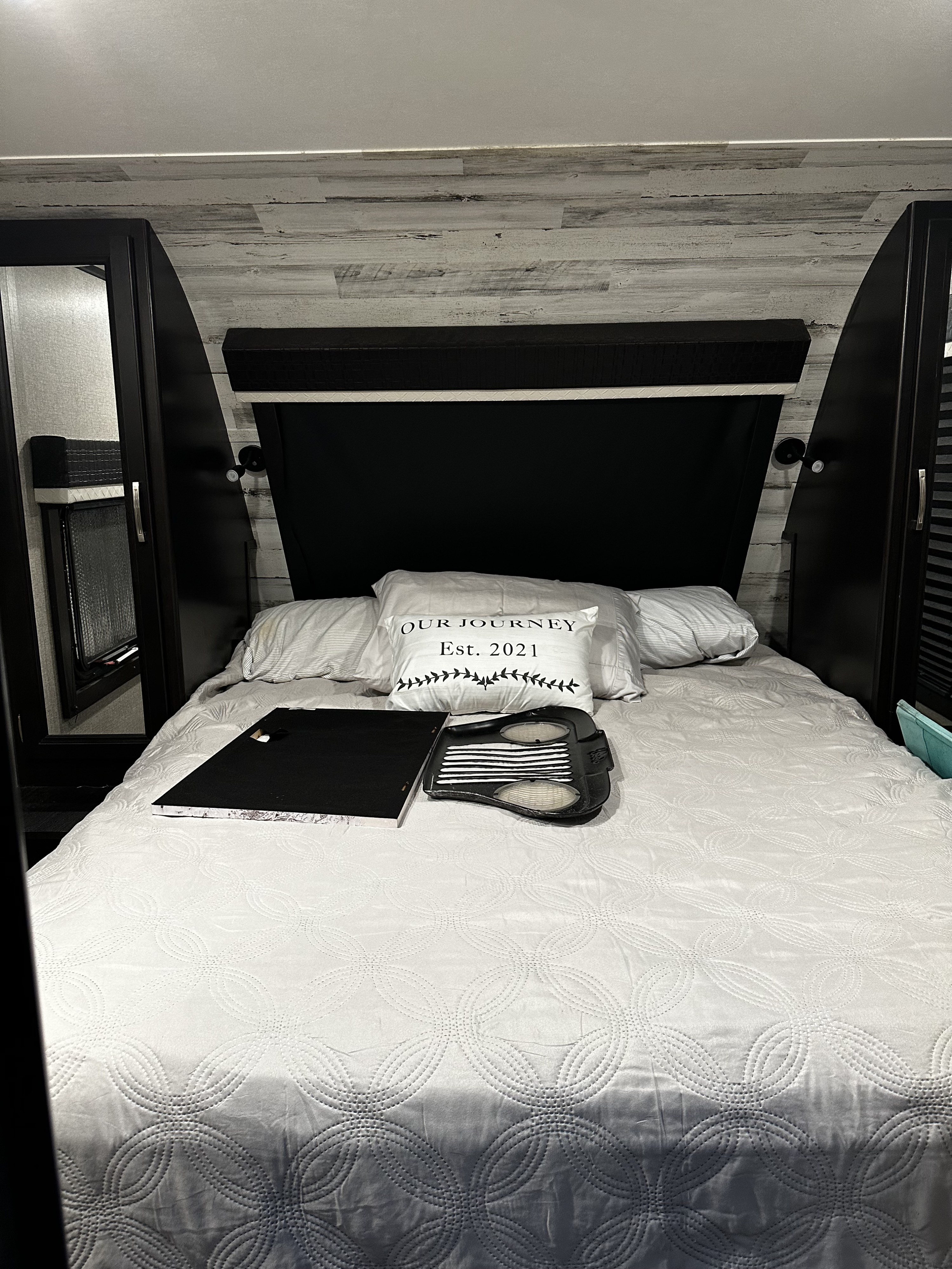 This cozy RV rental bedroom features a comfy bed with white quilted bedding, a custom pillow, and built-in cabinets.. Jayco White Hawk 2021