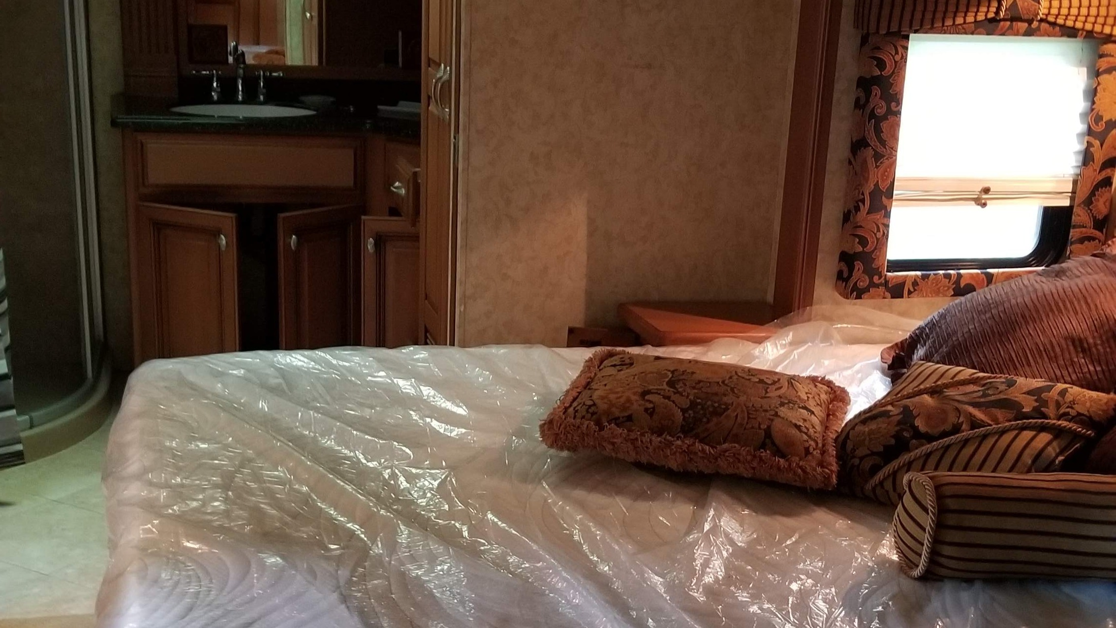 RV rental interior showcasing a clean bedroom with a plastic-covered mattress, decorative pillows, and an attached bathroom vanity.. Travel Supreme M-41MBH-4 2007