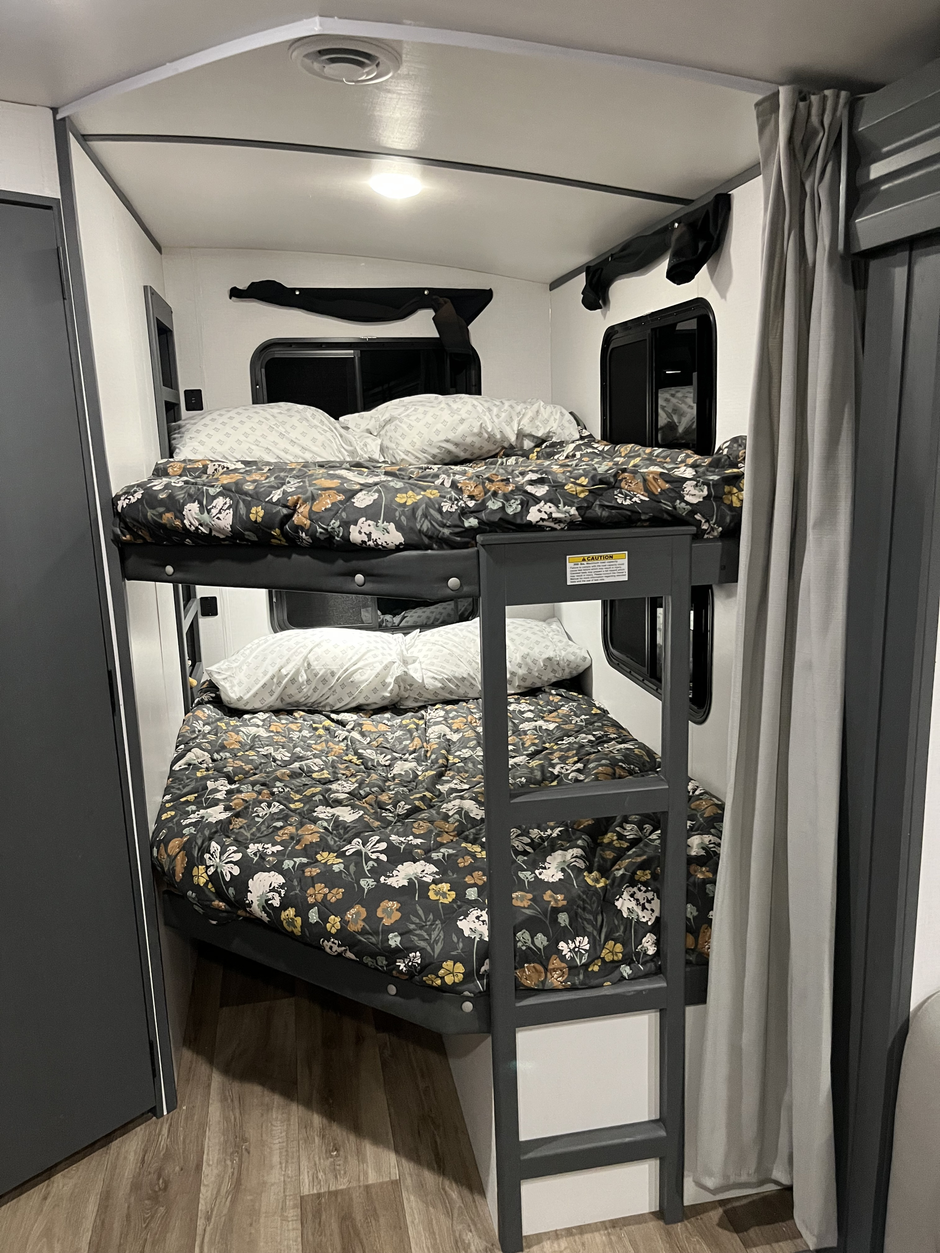 Cozy RV rental bunk beds with floral comforters and white pillows, set in a modern camper interior.. Keystone RV Bullet Ultra Lite 2022