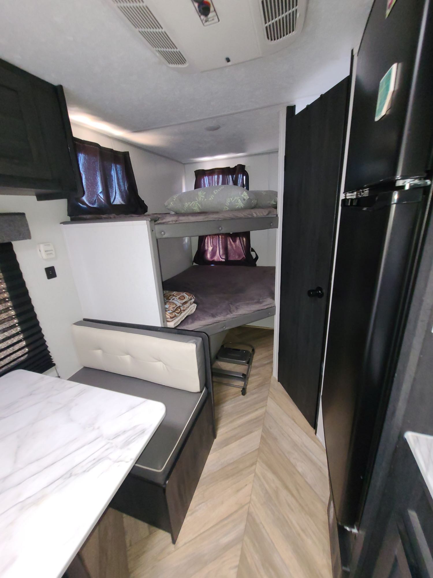 RV rental: modern interior featuring bunk beds, dinette, and full fridge on herringbone wood-look floor.. Forest River Ozark 2022