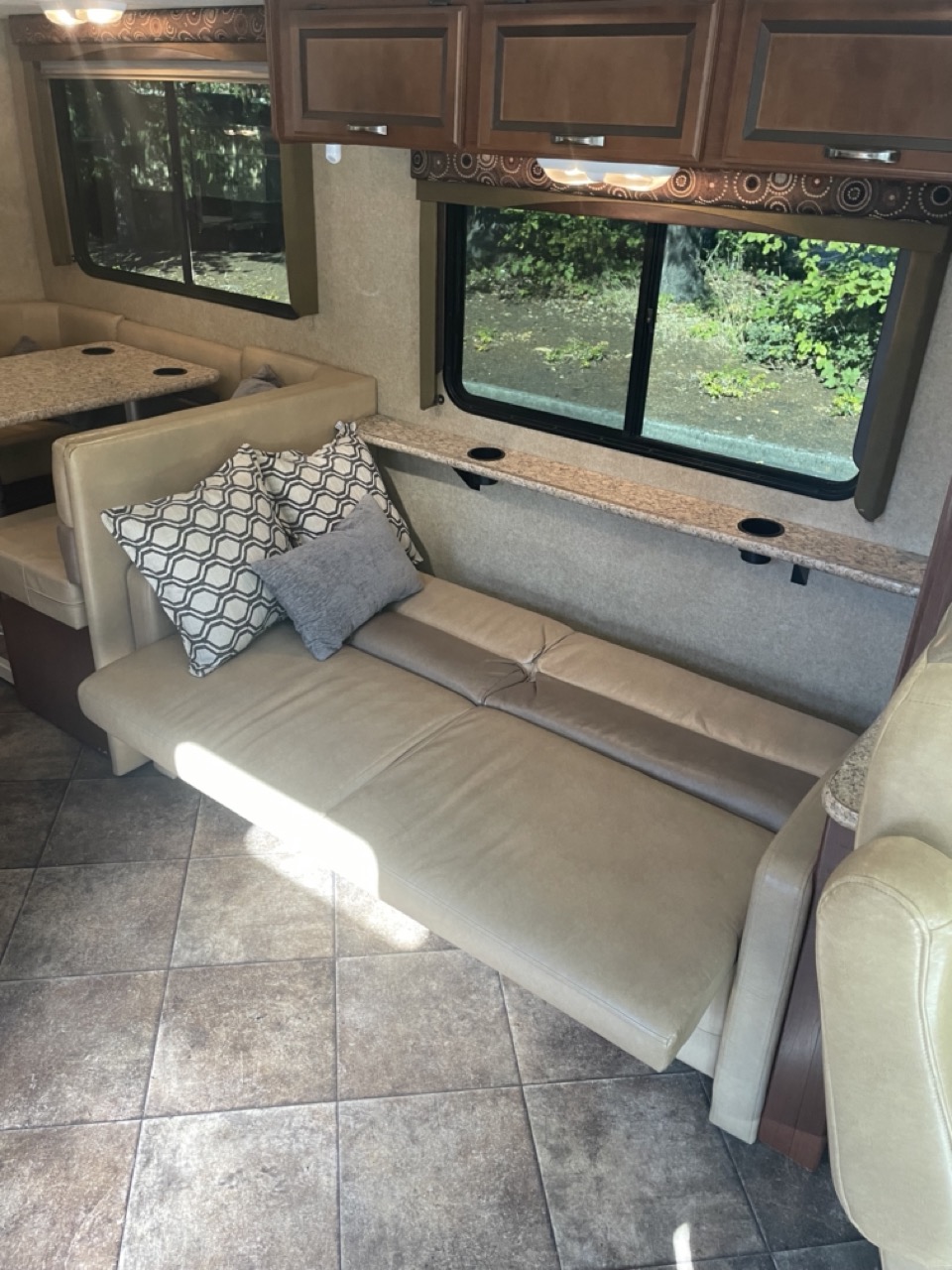 Comfortable RV rental interior showcasing a dinette, extended sofa bed, and overhead cabinets. Ideal for travel.. Thor A.C.E. 30.1 EVO 2014