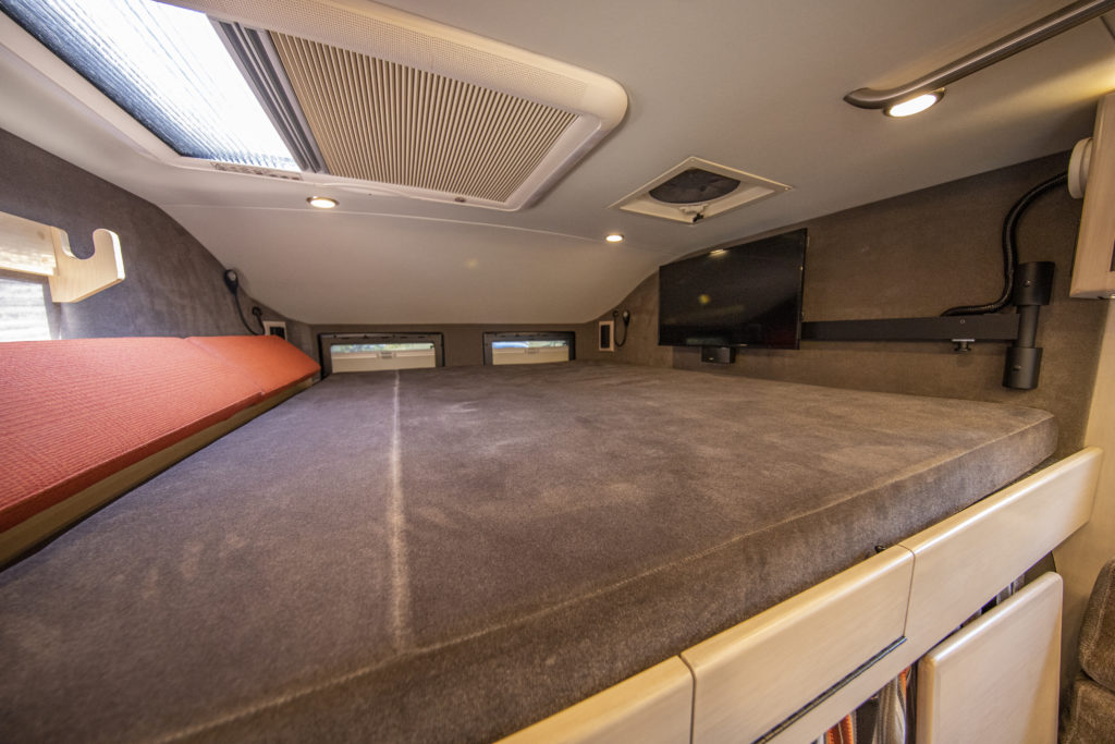 RV rental bedroom: a large, comfortable bed, mounted TV, skylight, and multiple windows for scenic views and light.. Earthroamer Xv-Lt 2018