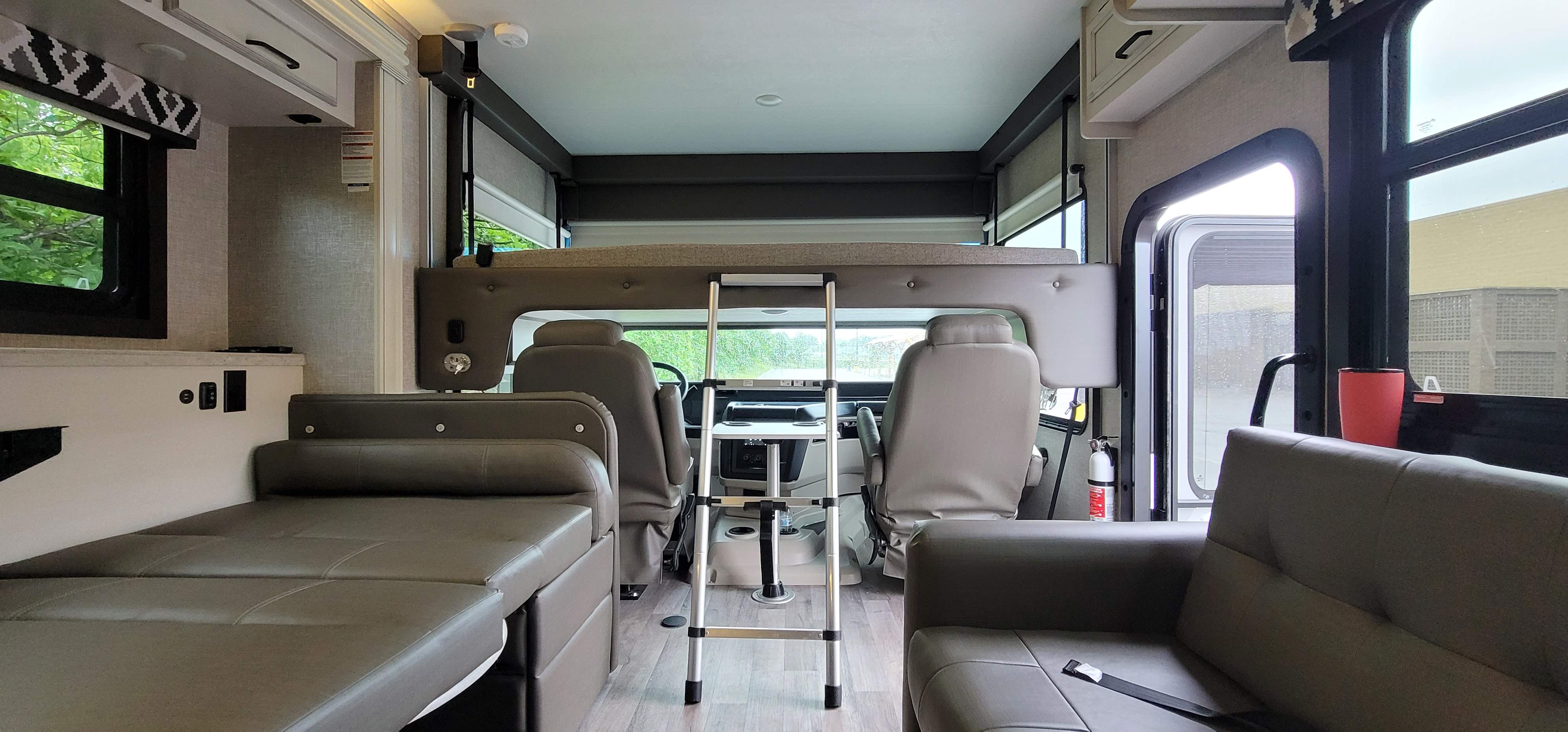 RV rental interior: A cozy cab-over bunk with ladder, spacious dinette/sofa, and driver's area. Modern and ready for travel!. Jayco Alante 2022