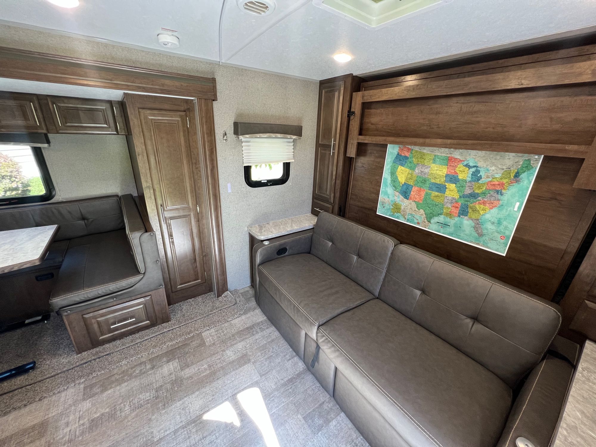Inside a cozy RV rental: shows a brown sofa, dinette with seating, wood cabinets, and a colorful US map on the wall.. Forest River Rockwood Mini Lite 2020