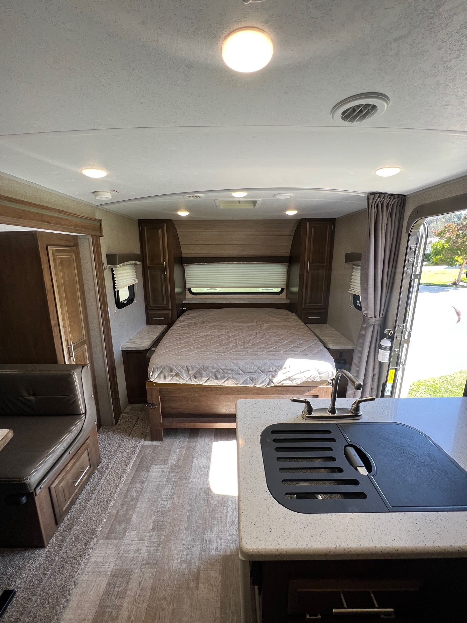 View of a modern RV rental interior, showcasing the main bed, compact kitchen area, and dinette seating.. Forest River Rockwood Mini Lite 2020