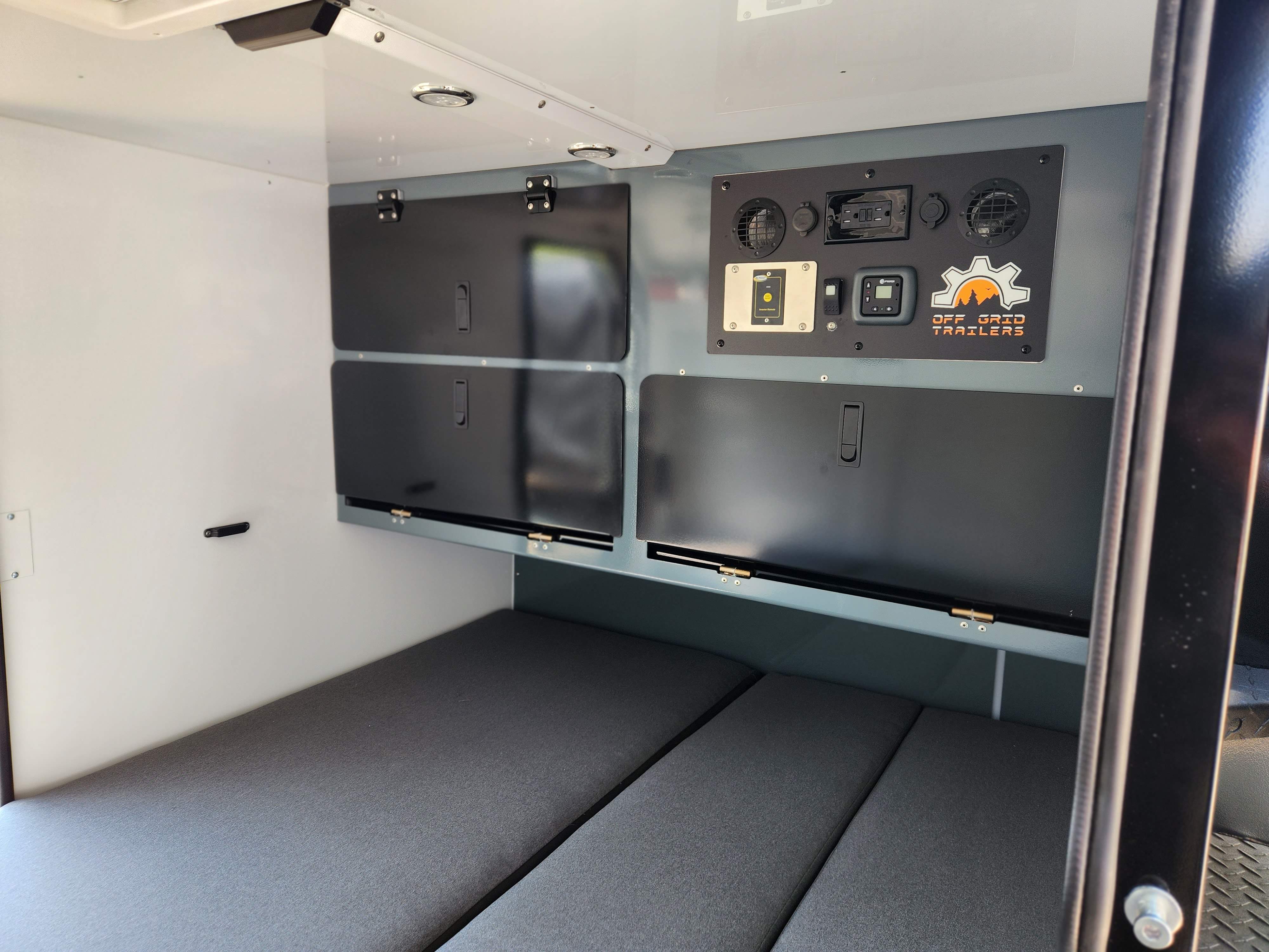 Interior of an Off Grid Trailers RV rental: cozy sleeping area, integrated storage, and a functional control panel.. Off Grid Trailers Off Grid Trailers Trailer 2022