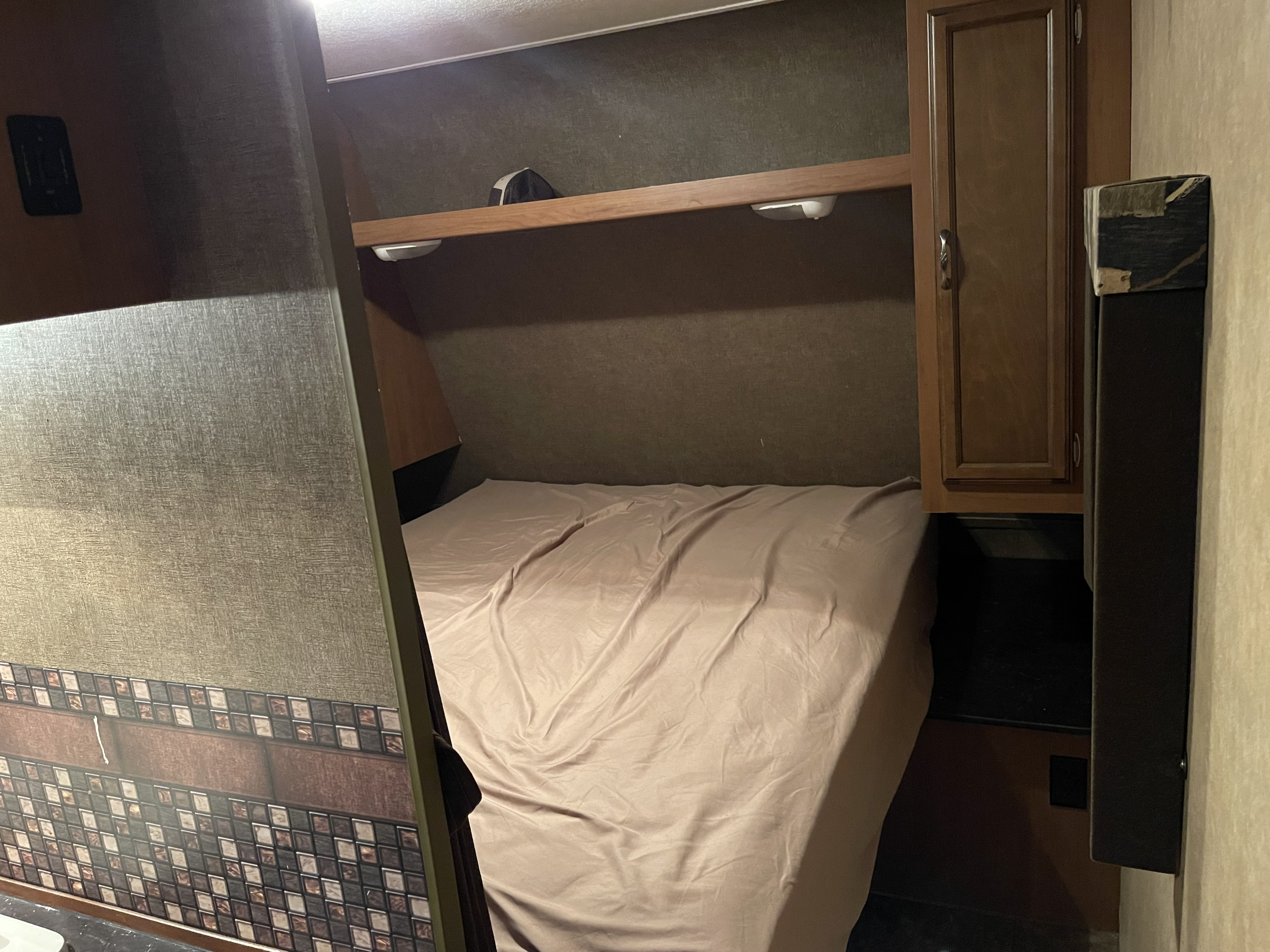 An RV rental bedroom featuring a bed, overhead shelf with lights, and compact cabinetry.. Starcraft Launch Ultra Lite 2015
