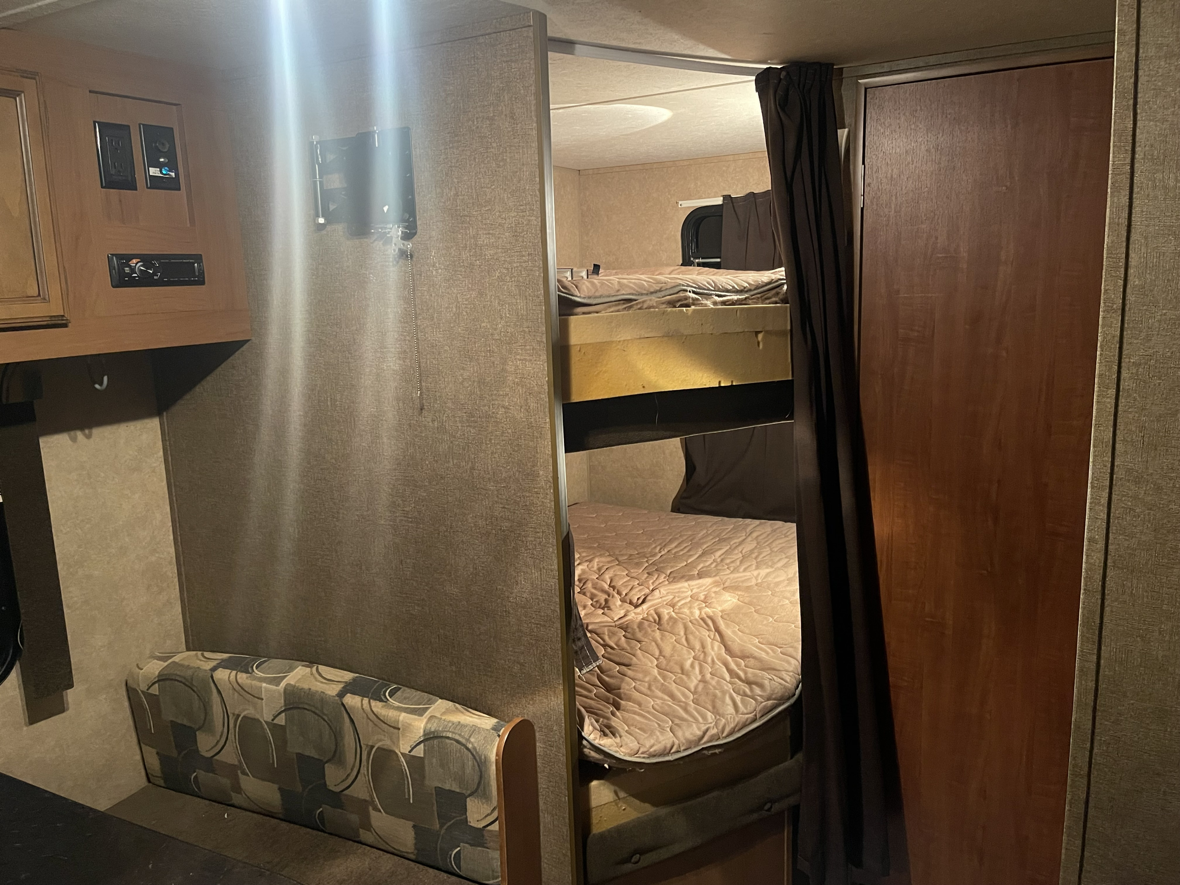 Inside an RV rental featuring a bunk bed sleeping area, a dinette seat, and entertainment controls on the wall.. Starcraft Launch Ultra Lite 2015