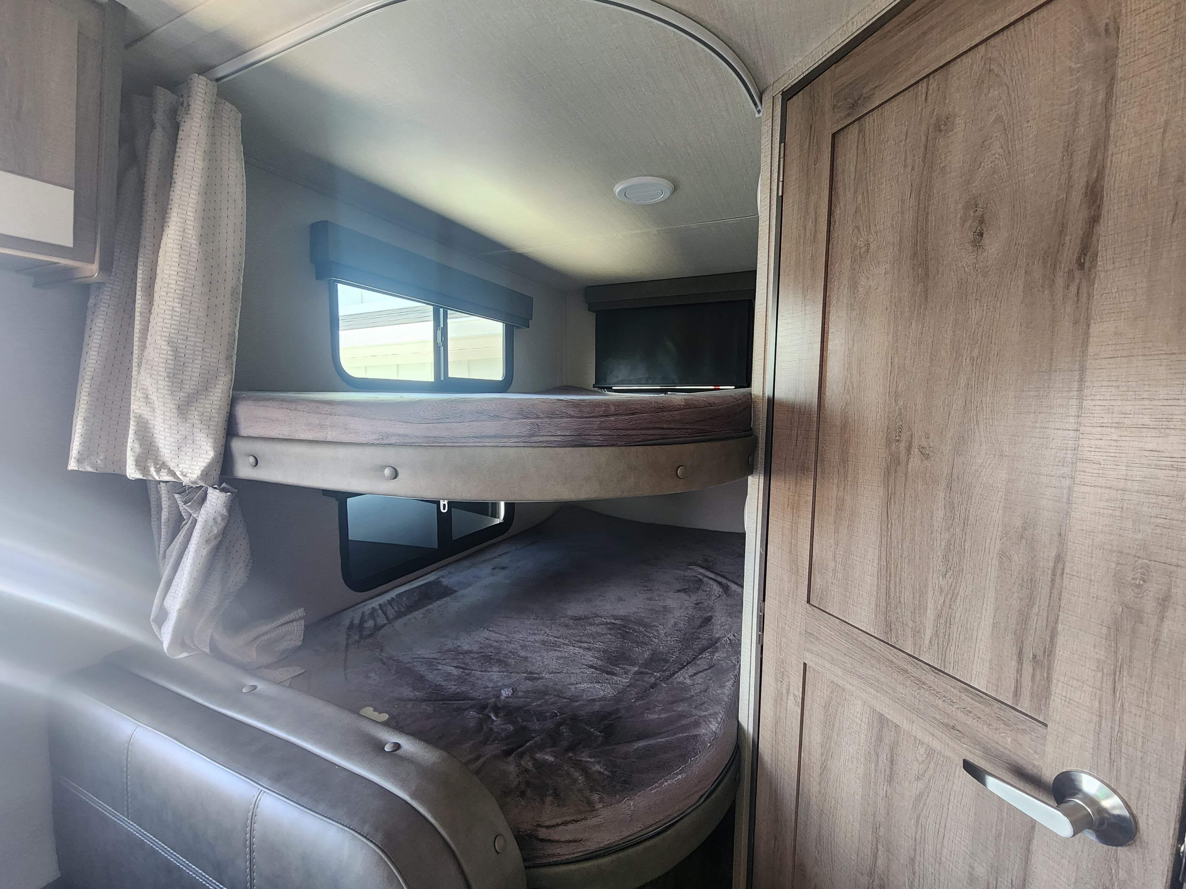 RV rental interior with comfy bunk beds, windows, and a door, ideal for families.. Grand Design Imagine XLS 2022