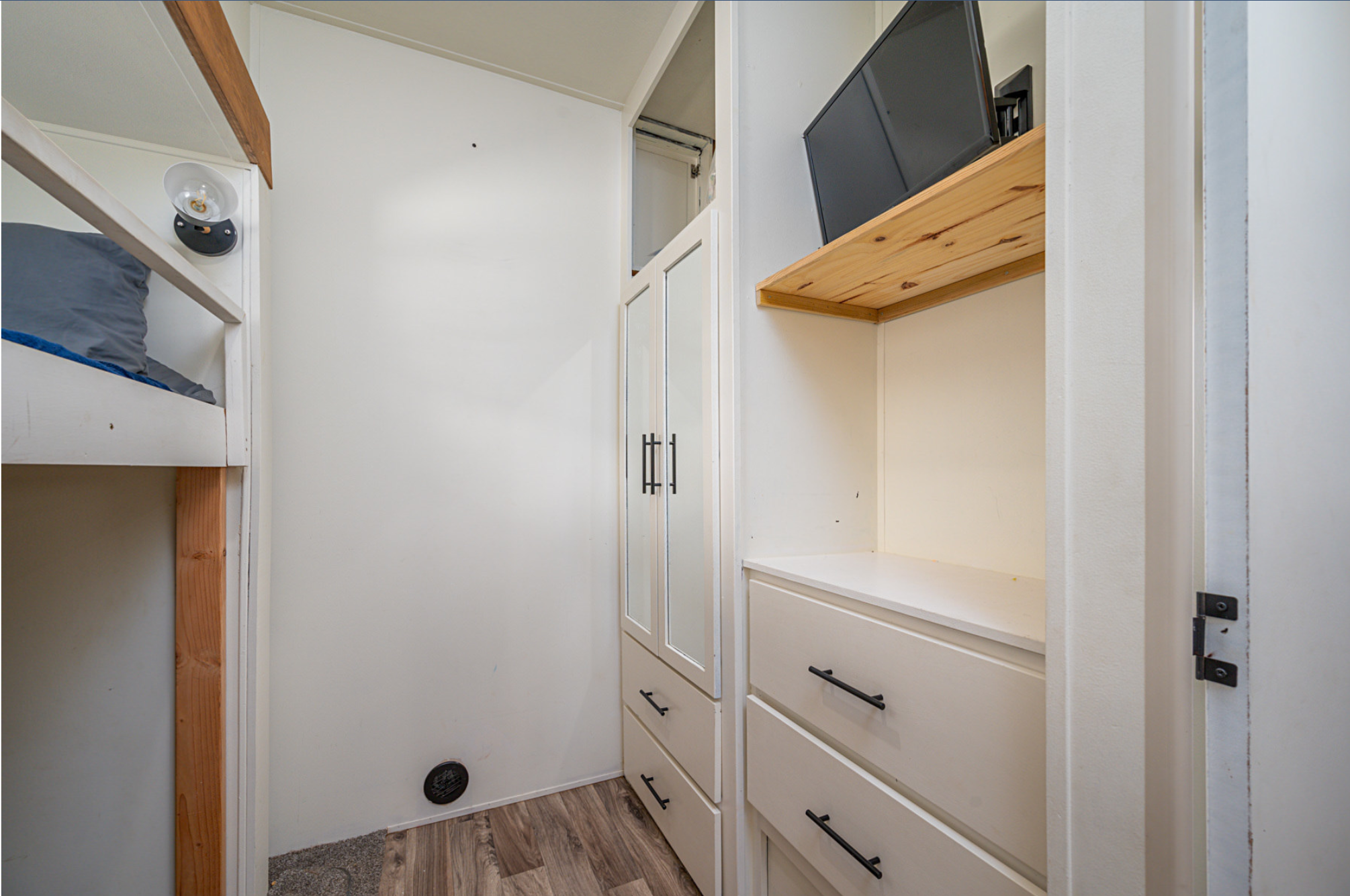 RV rental interior shows bunk beds, mirrored cabinets, storage drawers, and a mounted TV.. Forest River Wildwood Heritage Glen Lite 2018