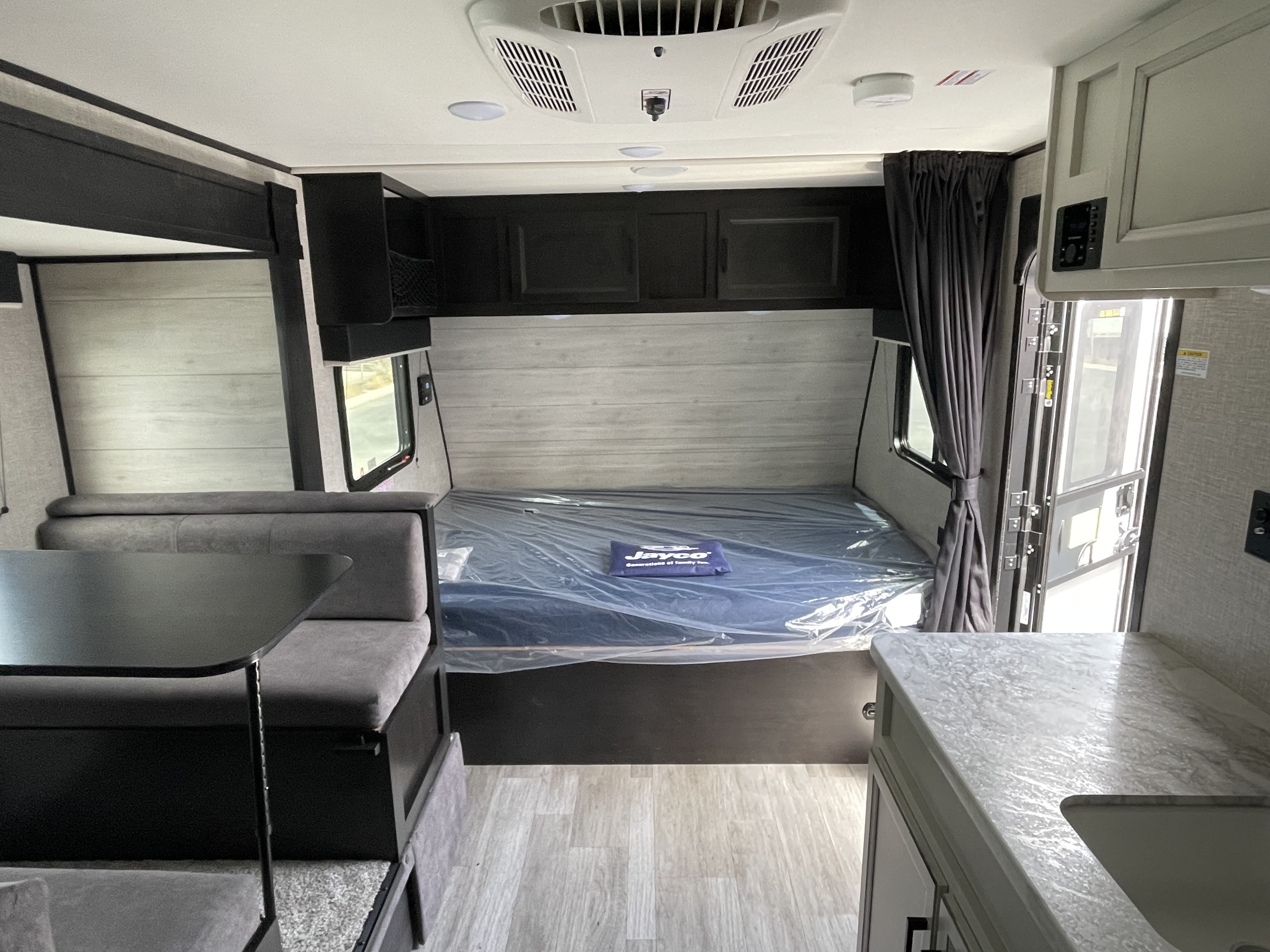 Modern RV rental interior with dinette, bed wrapped in plastic, and kitchen area. Bright, clean, and ready for trips.. Jayco Jay Flight SLX Baja Edition 2022