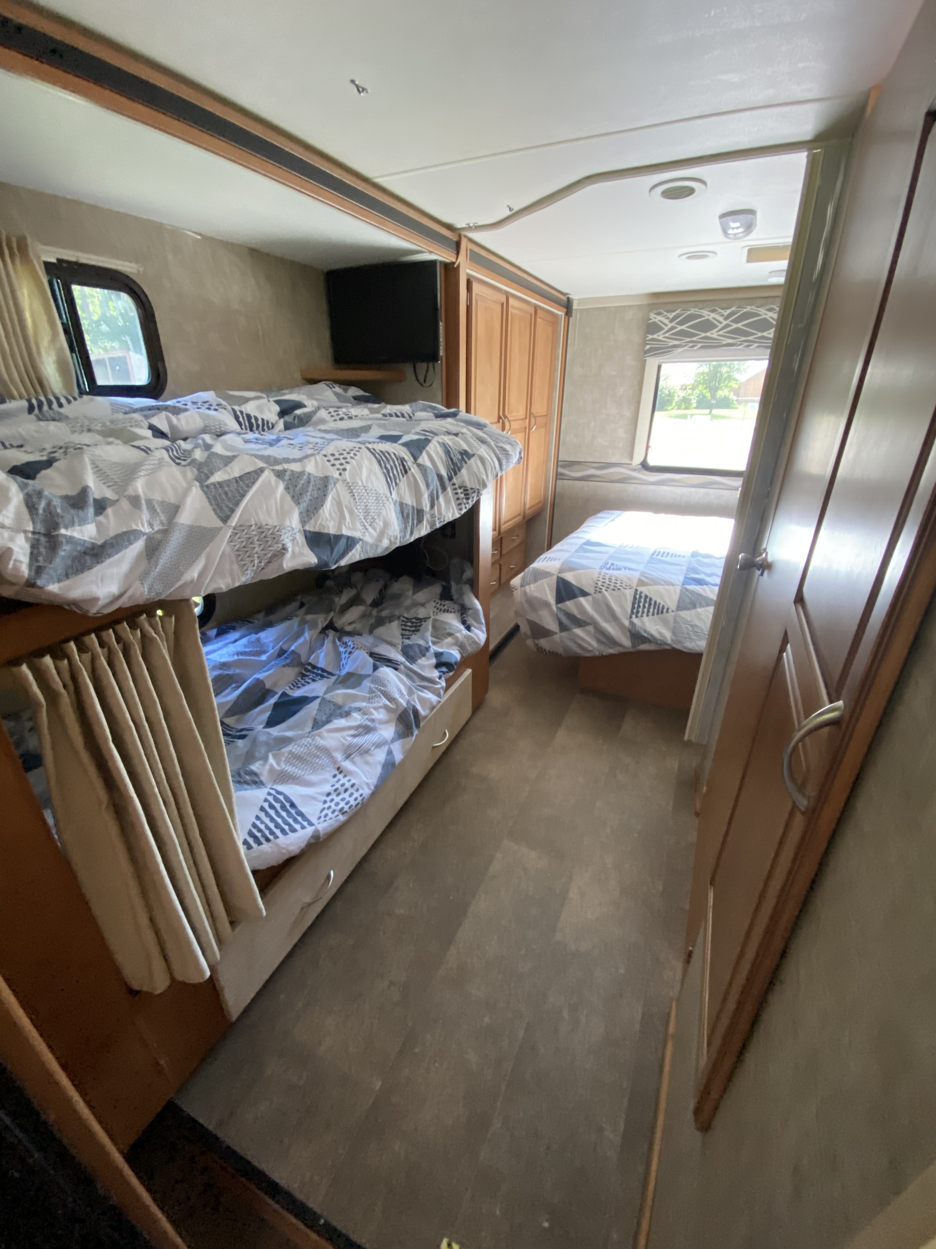 Experience an RV rental! Interior view of a comfortable sleeping area with bunk beds, a TV, and an additional bed.. Winnebago Minnie Winnie 2015