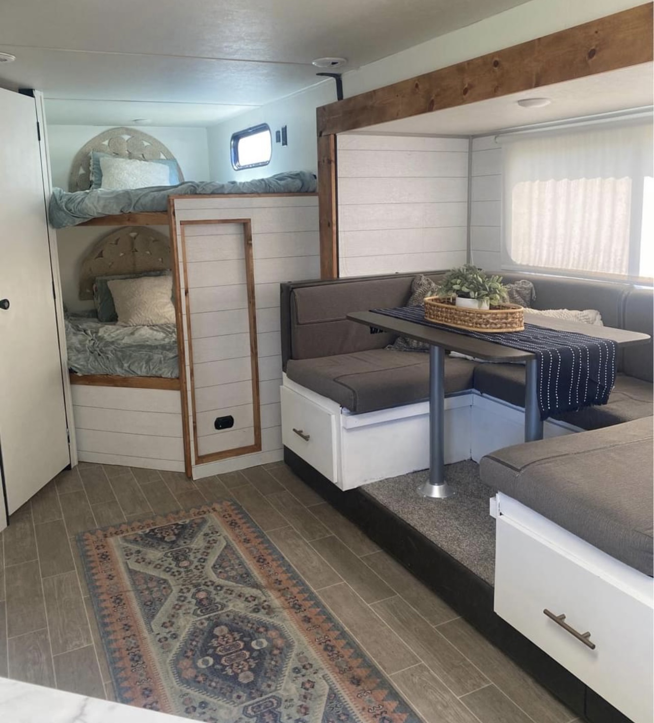 Inside a modern RV rental: built-in bunk beds, U-shaped dinette, and chic wood accents. Comfortable travel awaits!. Forest River Cherokee Grey Wolf 2021