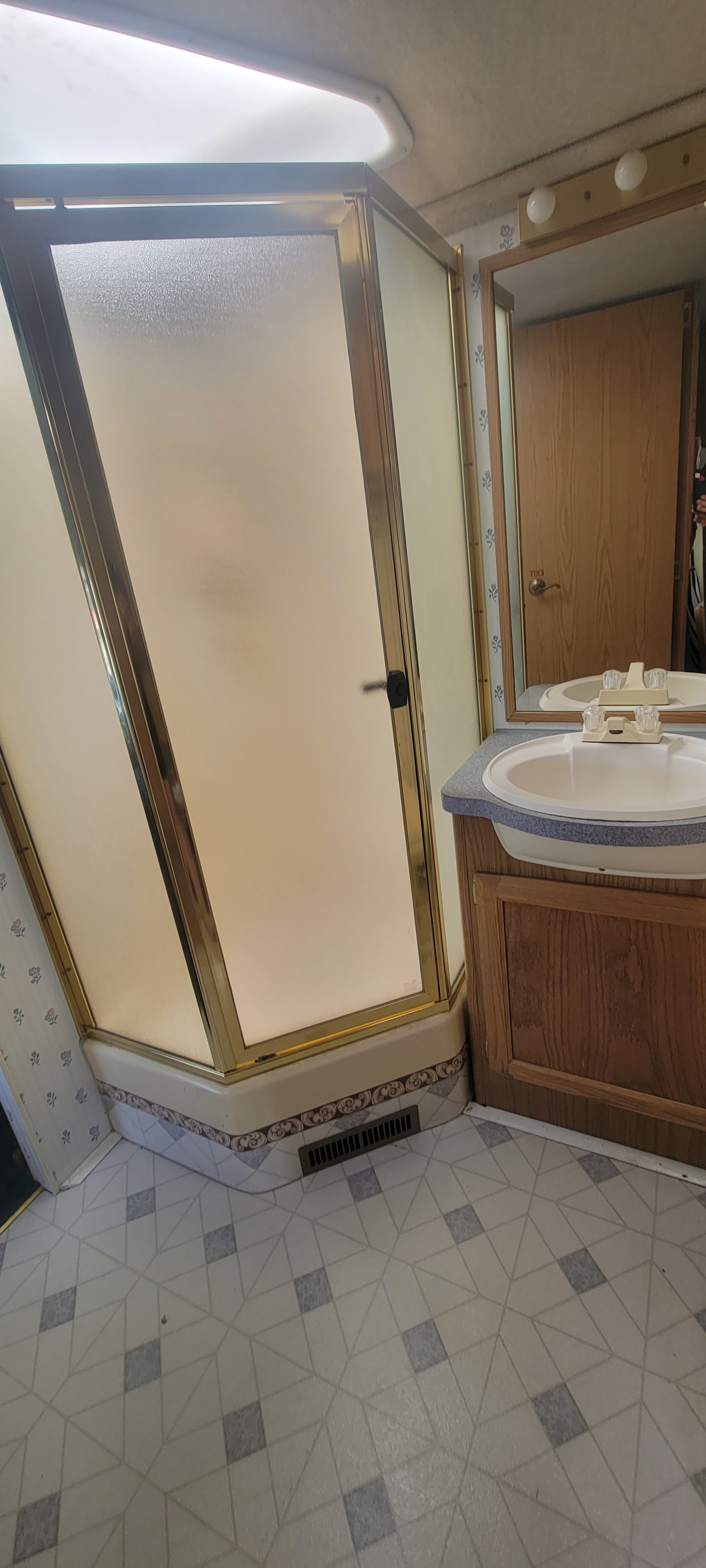 Compact RV bathroom with a corner shower, vanity, and mirror, ideal for your next RV rental journey.. Pace-Arrow 35' 1996