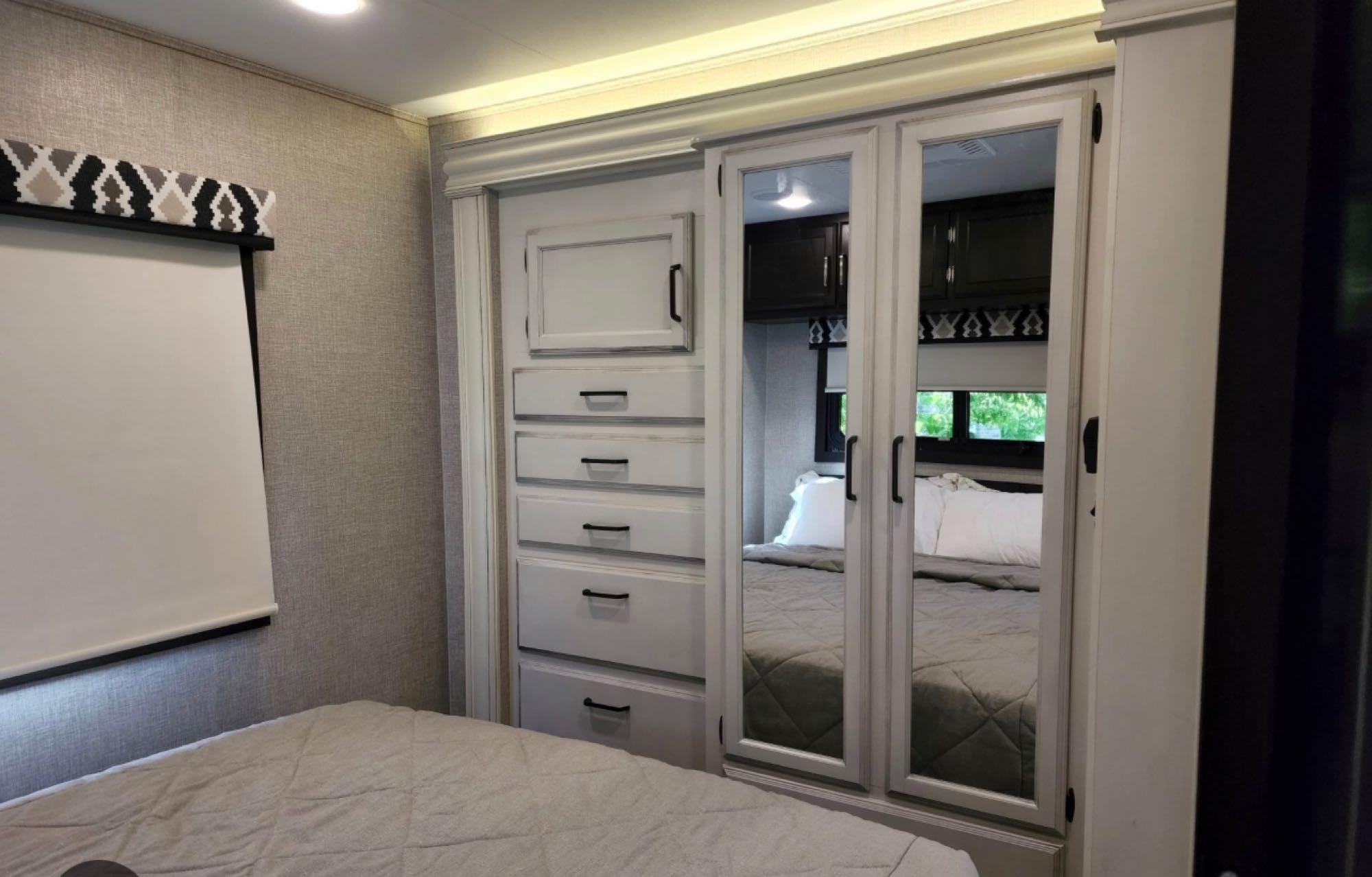Inside an RV rental: modern bedroom featuring a comfortable bed, built-in storage, and mirrored closet.. Jayco Alante 29F 2023