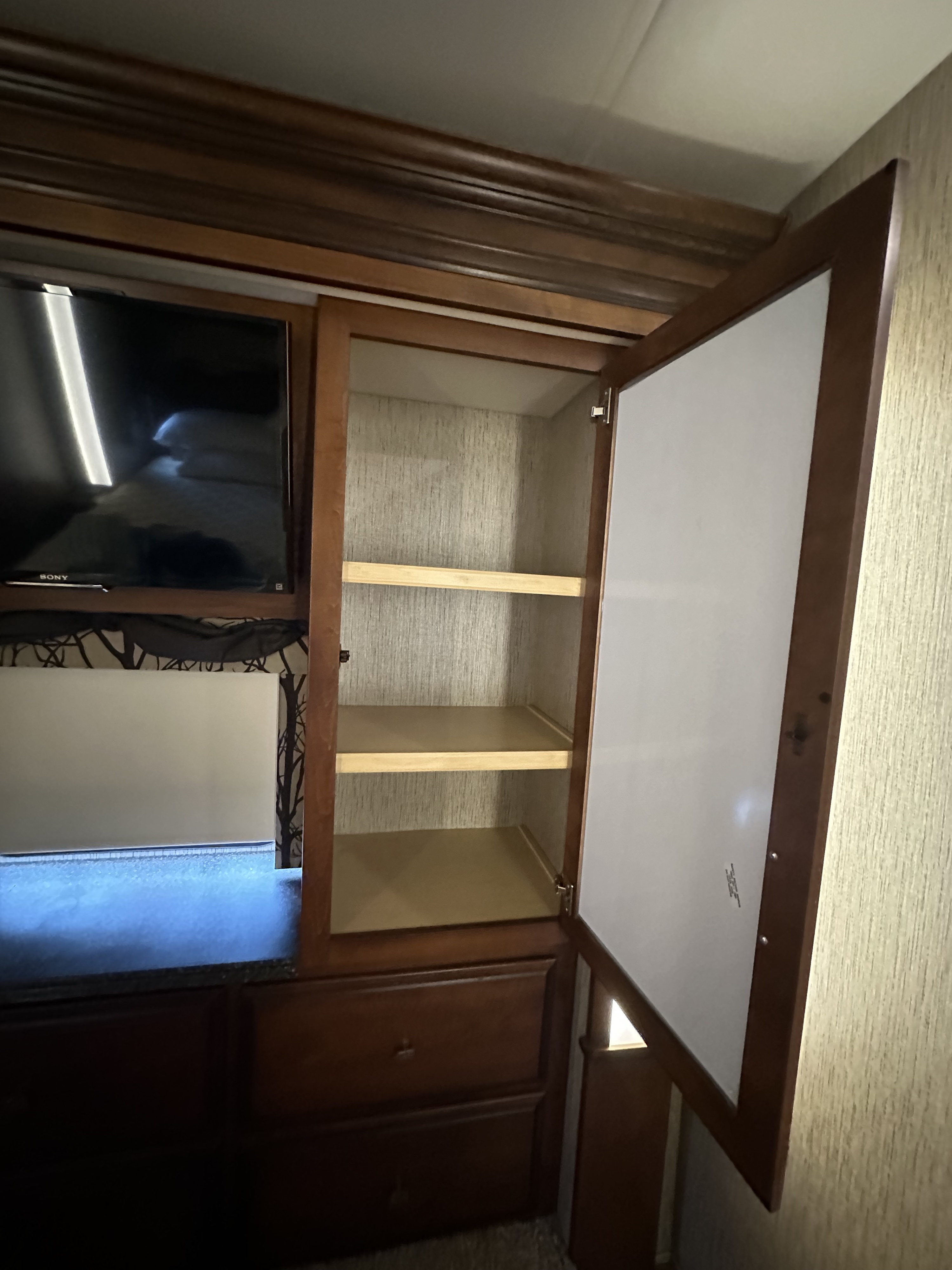 RV rental interior: A clean, open wood cabinet with shelves, Sony TV, and drawers. Practical storage space for your trip.. Newmar Canyon Star 2016