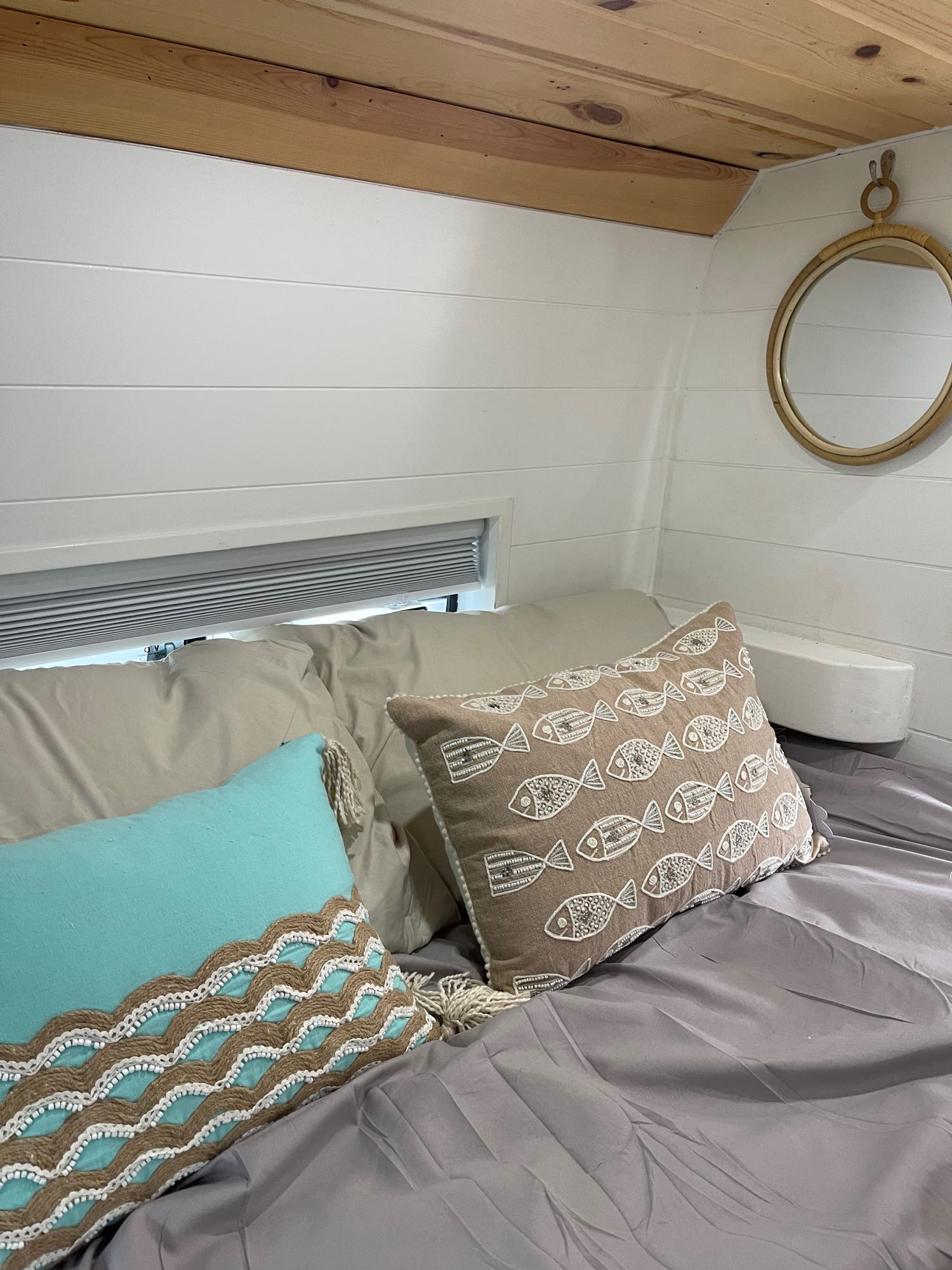 Cozy RV rental bedroom: wood ceiling, white walls, mirror, and bed with marine-themed & turquoise pillows.. Dodge Pro Master 2021