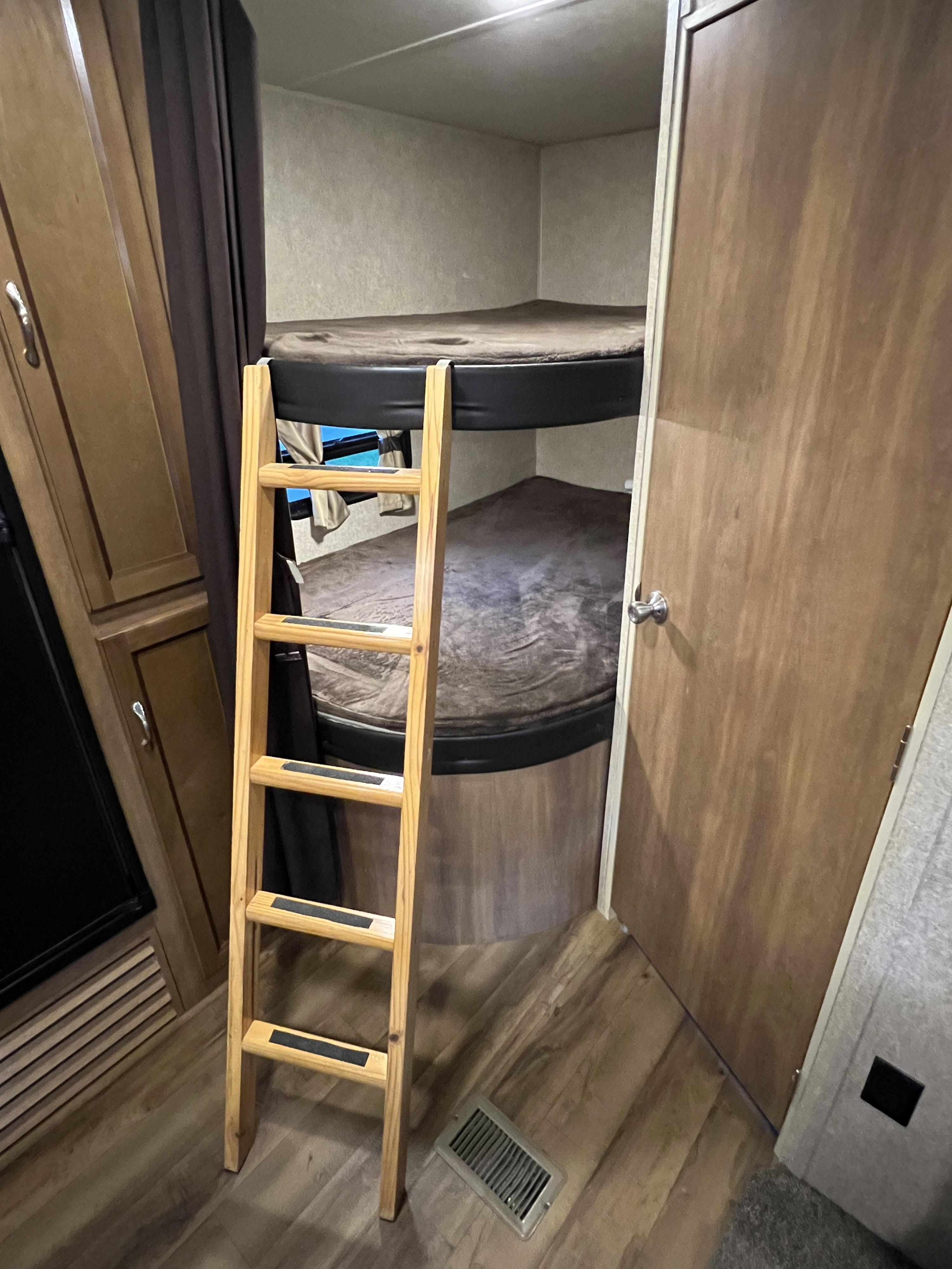RV rental bunk beds with a ladder, featuring wood-look flooring and interior cabinetry. Ideal for family travel.. Coachmen Catalina 2017