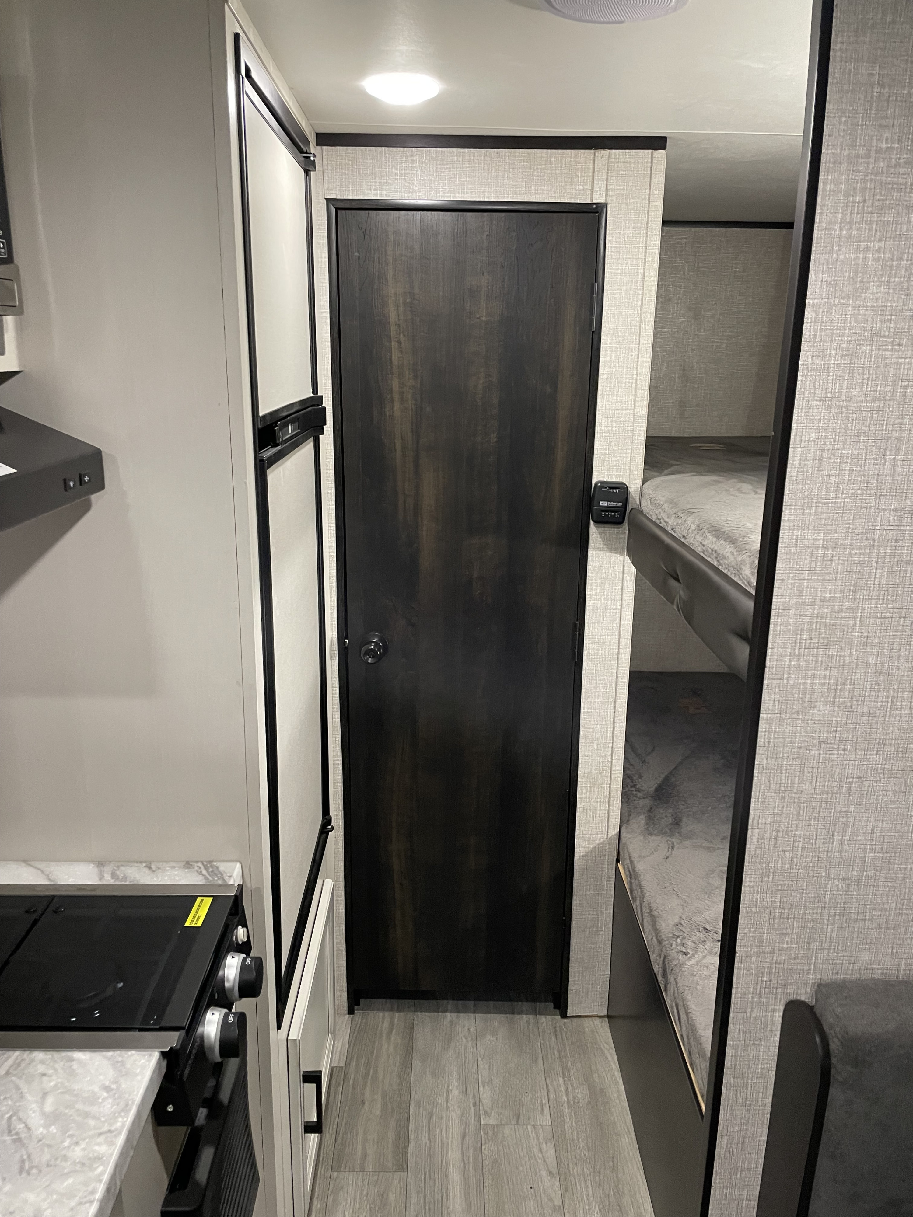 RV rental showcasing a compact kitchen with stove & fridge, a central door, and bunk beds for family comfort.. Jayco Jay Flight SLX 2022