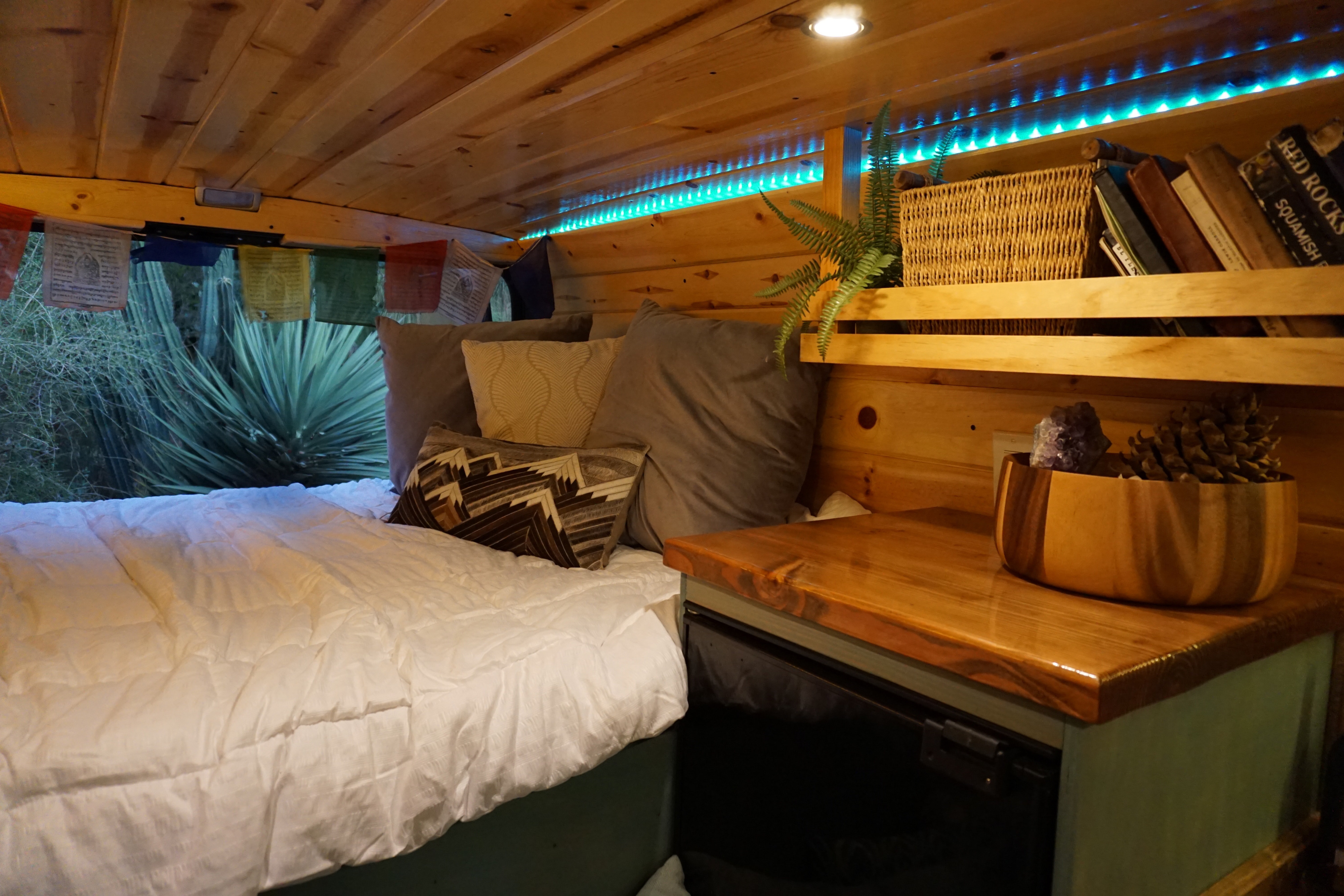 Cozy RV rental interior with wood paneling, comfortable bed, ambient blue lights, and clever storage solutions.. Dodge Sprinter Van 2018