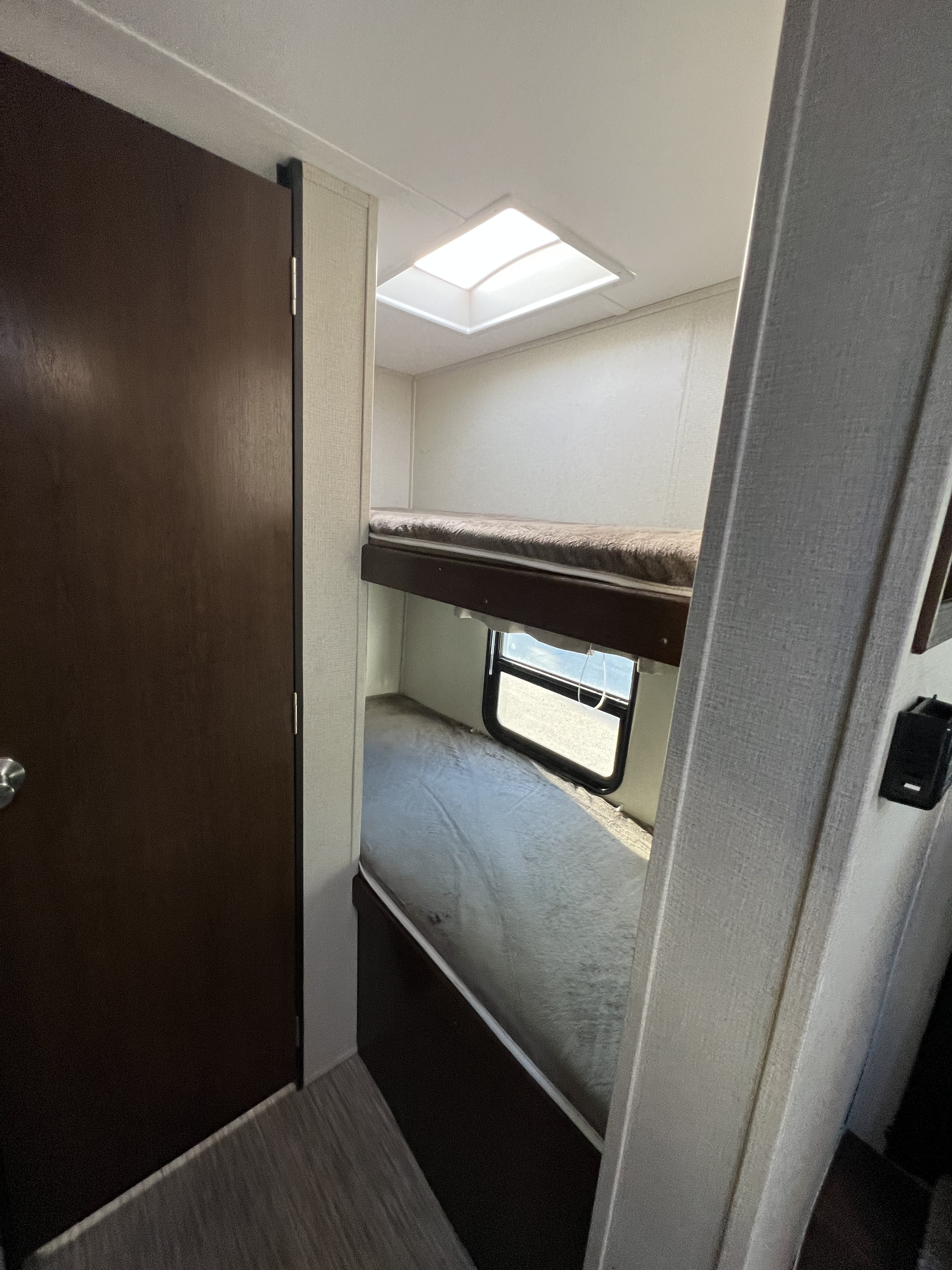 Compact RV rental sleeping area featuring cozy bunk beds, a window, and a bright skylight.. Navi Navi Trailer 2019