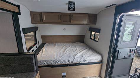 RV rental interior: comfortable bedroom featuring a bed, overhead cabinets, and side window view.. Forest River Wolfpup 2023