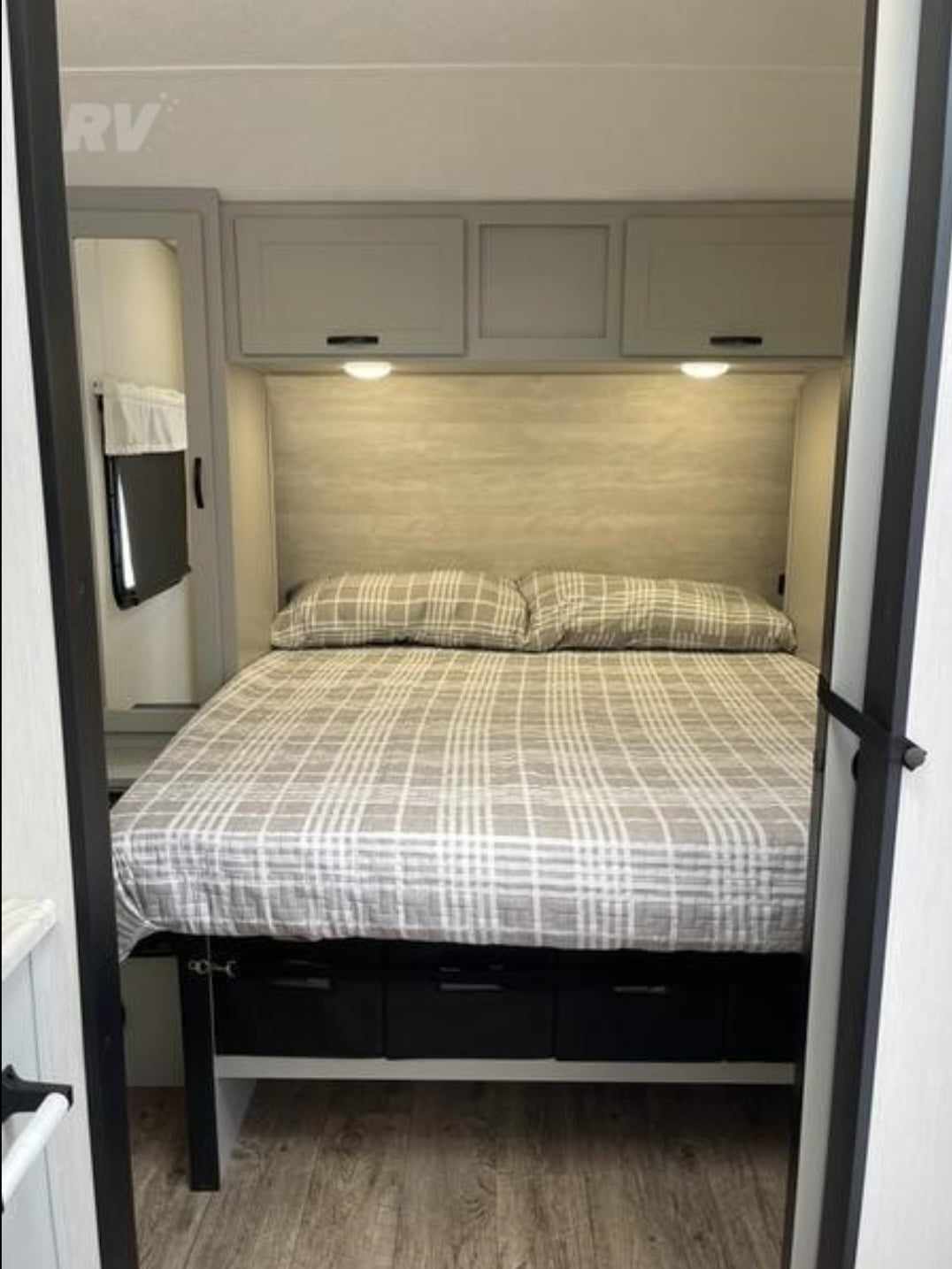 Modern RV rental bedroom with comfortable bed, overhead cabinets, and under-bed storage drawers. Perfect for travel.. Forest River Vibe 2022