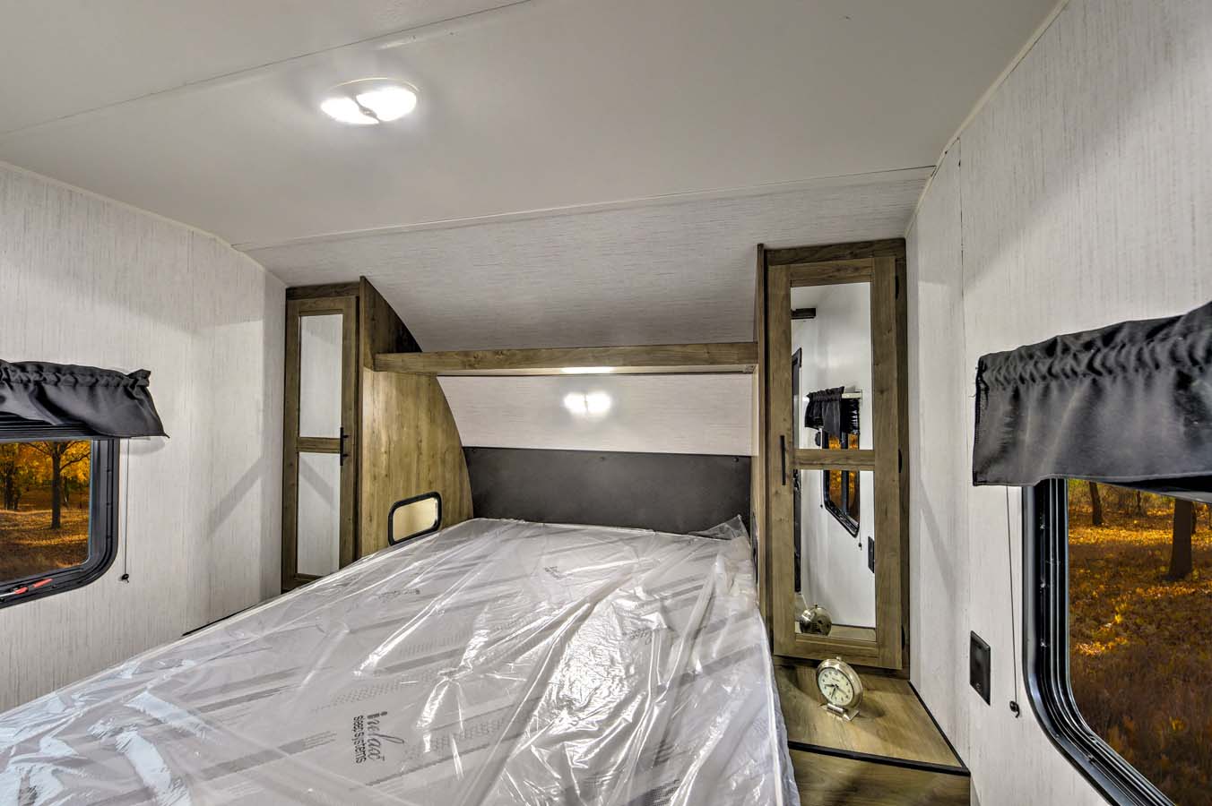 Cozy RV rental bedroom with a new bed, built-in storage, and scenic autumn window views. Ideal for your next trip!. Heartland RVs Pioneer 2022