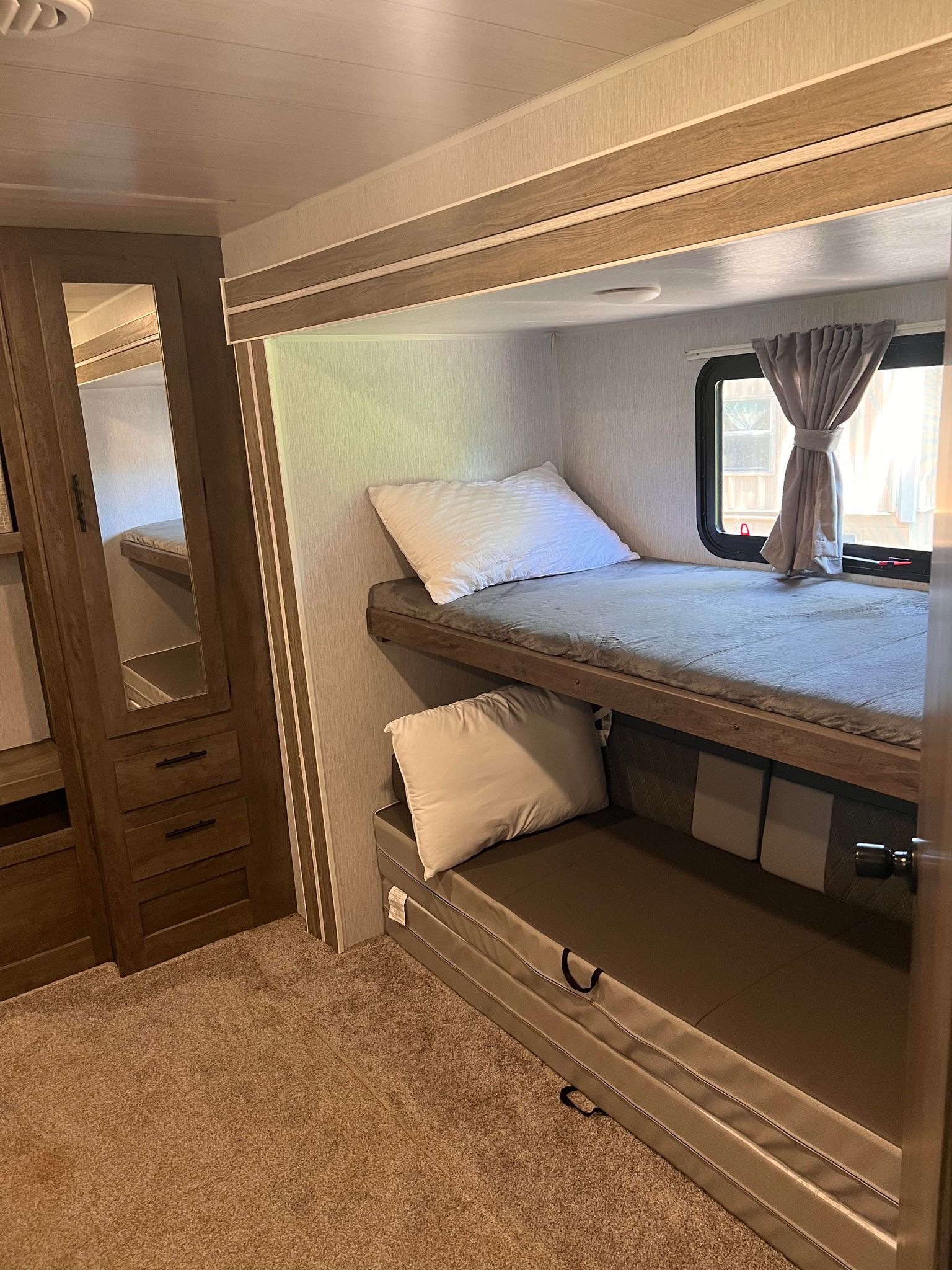 RV rental interior: A compact sleeping area with comfortable upper & lower bunk beds, mirrored wardrobe, and window.. Forest River Wildwood 2022