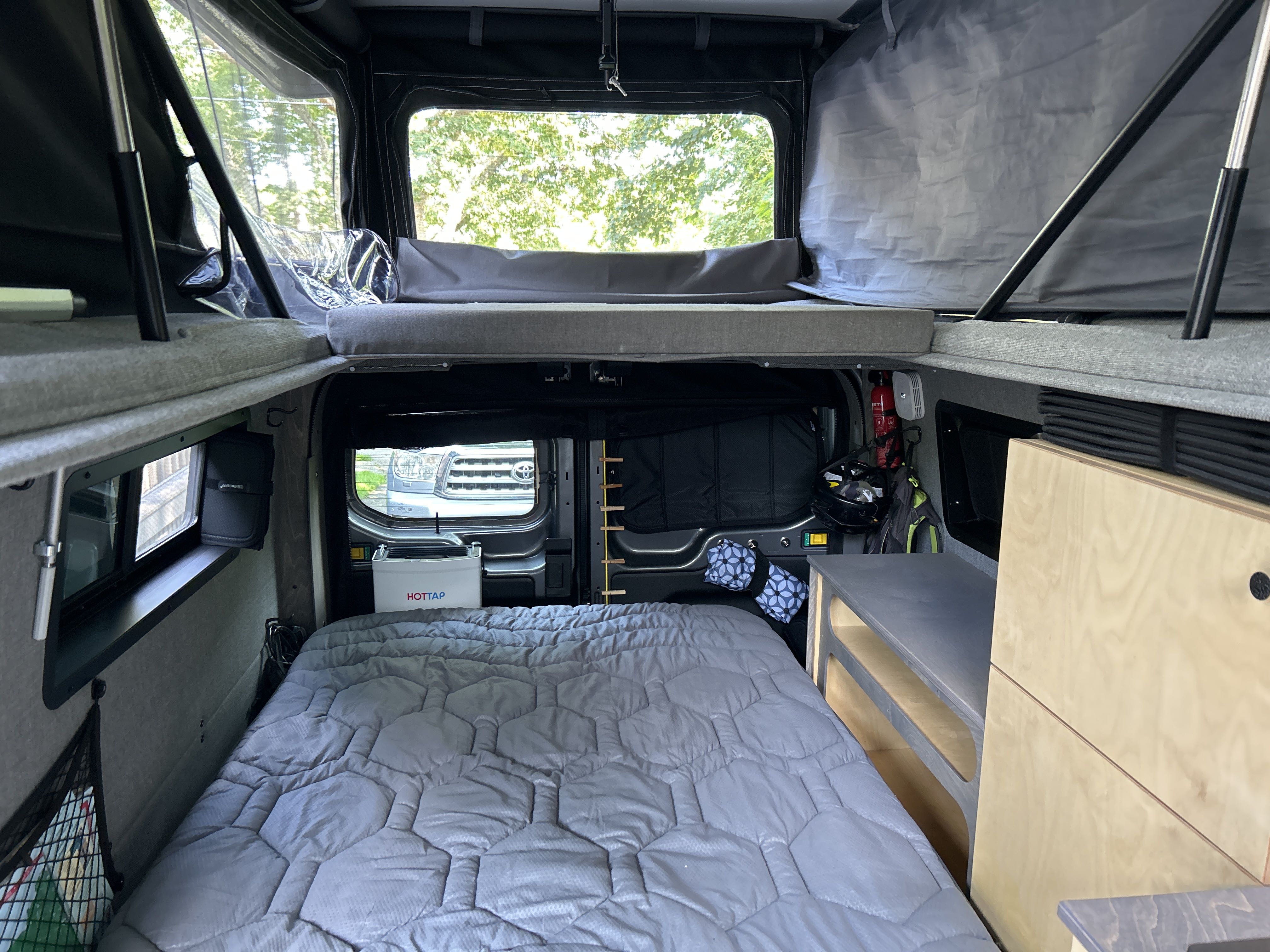 Inside a cozy RV rental camper van, featuring a main bed, a pop-top bed, and organized storage.. Ford Custom Transit 2022