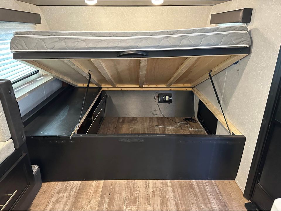 RV rental: Mattress lifted revealing under-bed storage with an electrical control panel. Practical space for your camper.. Forest River Cherokee Wolf Pup Black Label 2023