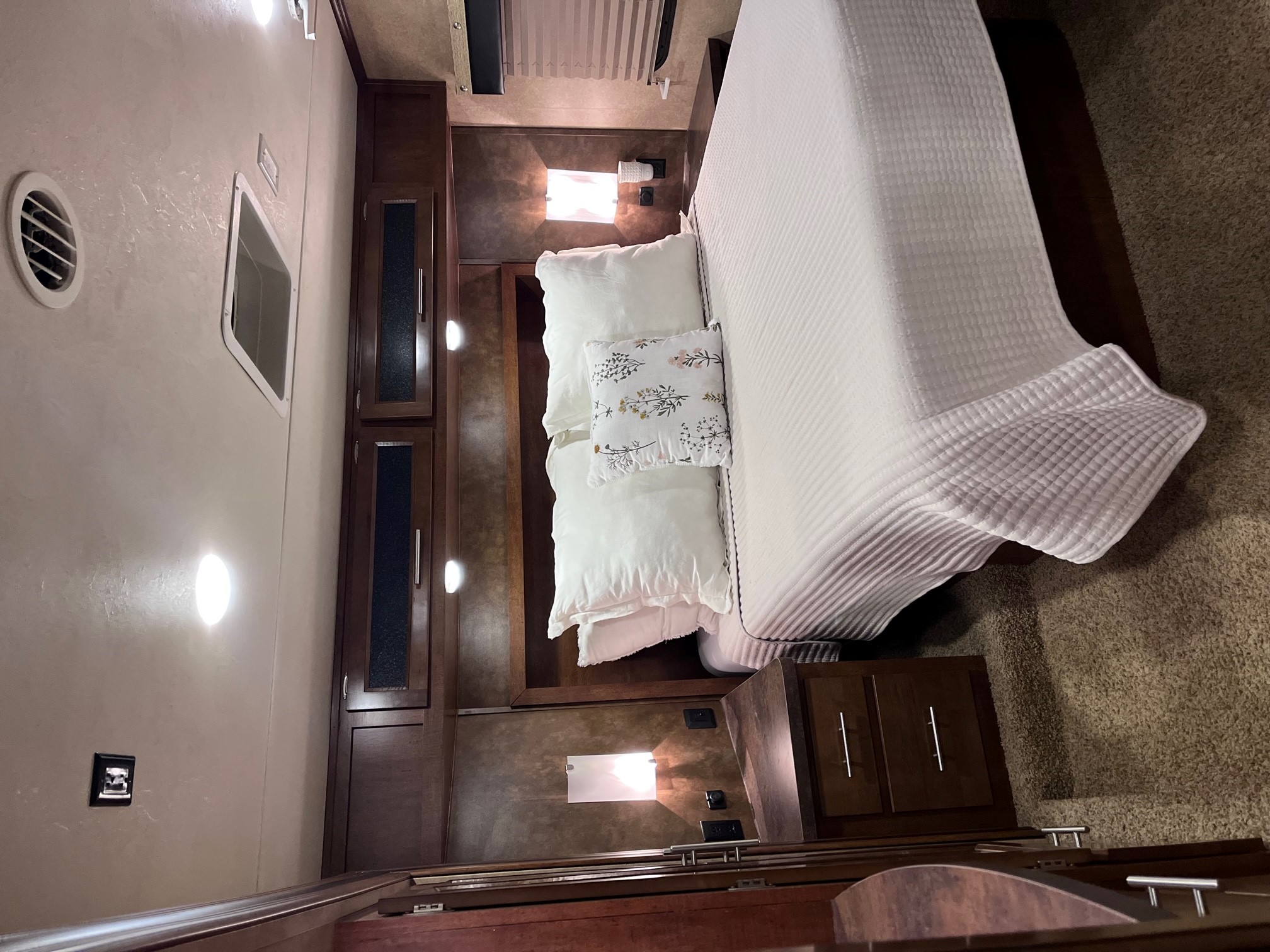 Cozy RV rental bedroom with white bedding, dark wood cabinets, and bright lighting, perfect for travel comfort.. Forest River Xlr Thunrderbolt 2014
