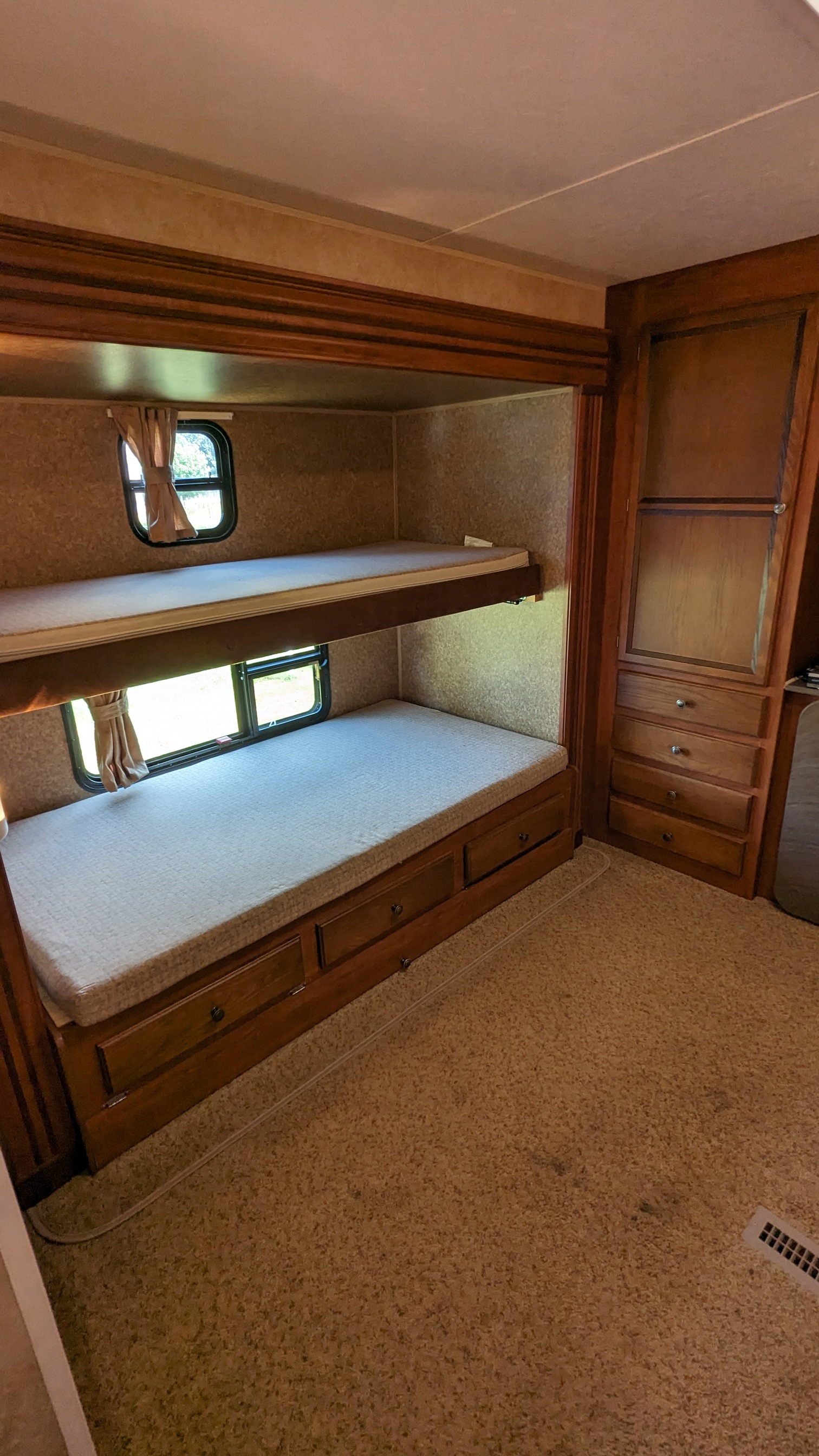Cozy RV rental bunk beds with windows, curtains, built-in storage, and carpeted flooring, ready for travel.. Jayco Jay Flight 2012