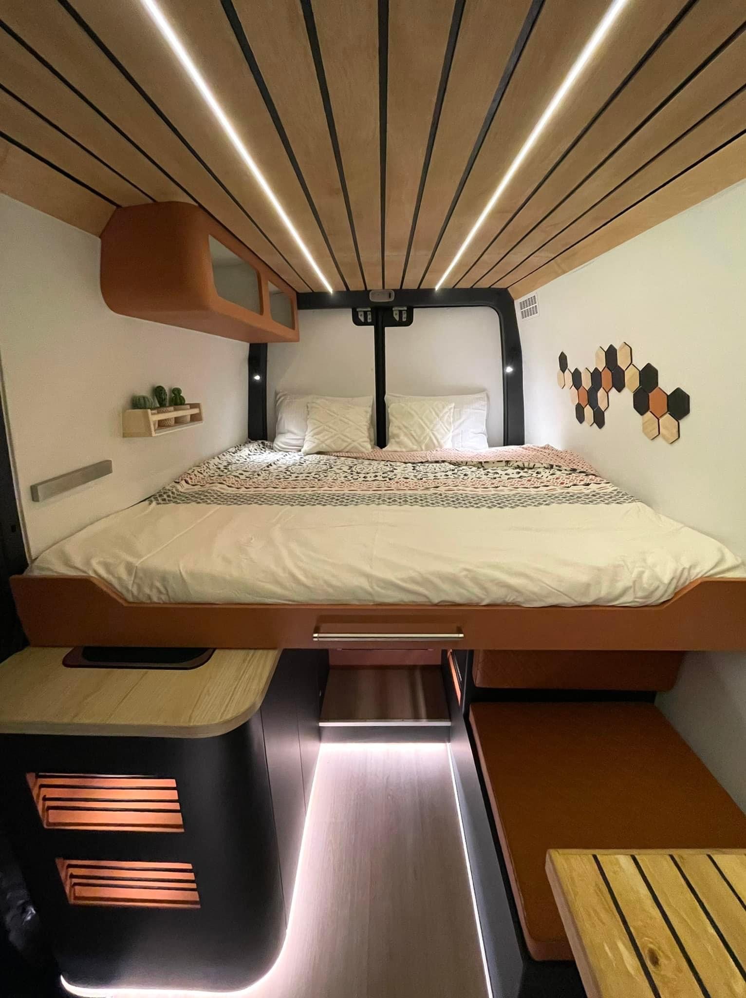 Inside a modern RV rental: elevated bed, wood slat ceiling with LED strips, and sleek storage solutions.. Mercedes sprinter 2018