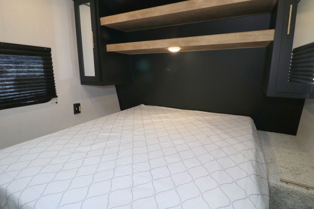 Cozy bedroom in an RV rental featuring a comfortable bed, overhead storage, and window. Perfect for your next adventure!. Keystone RV Springdale 2022
