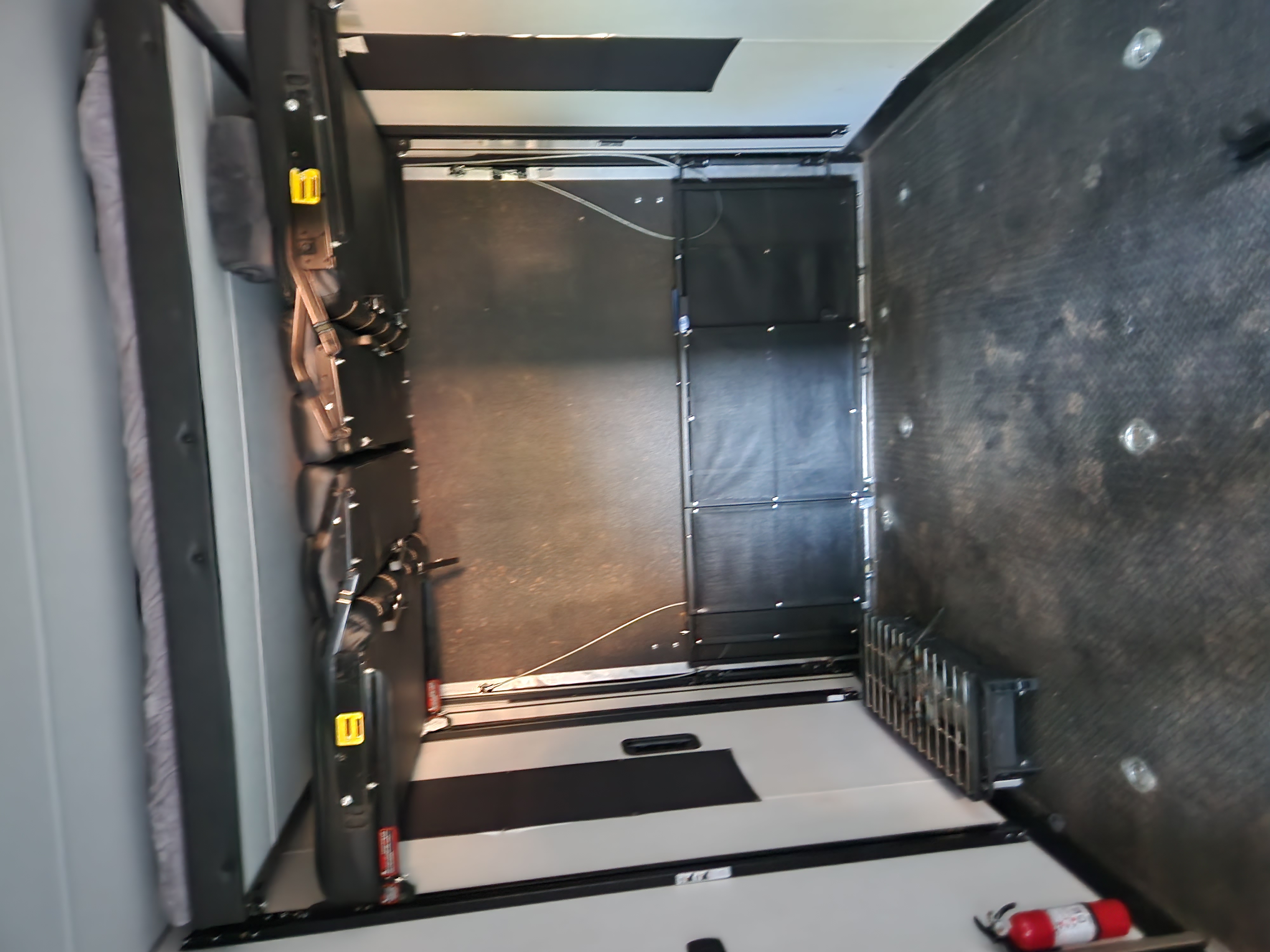 RV rental toy hauler interior shows folded bunk beds against wall, durable garage floor, and fire extinguisher.. Forest River Cherokee Wolf Pack Toy Hauler 2021