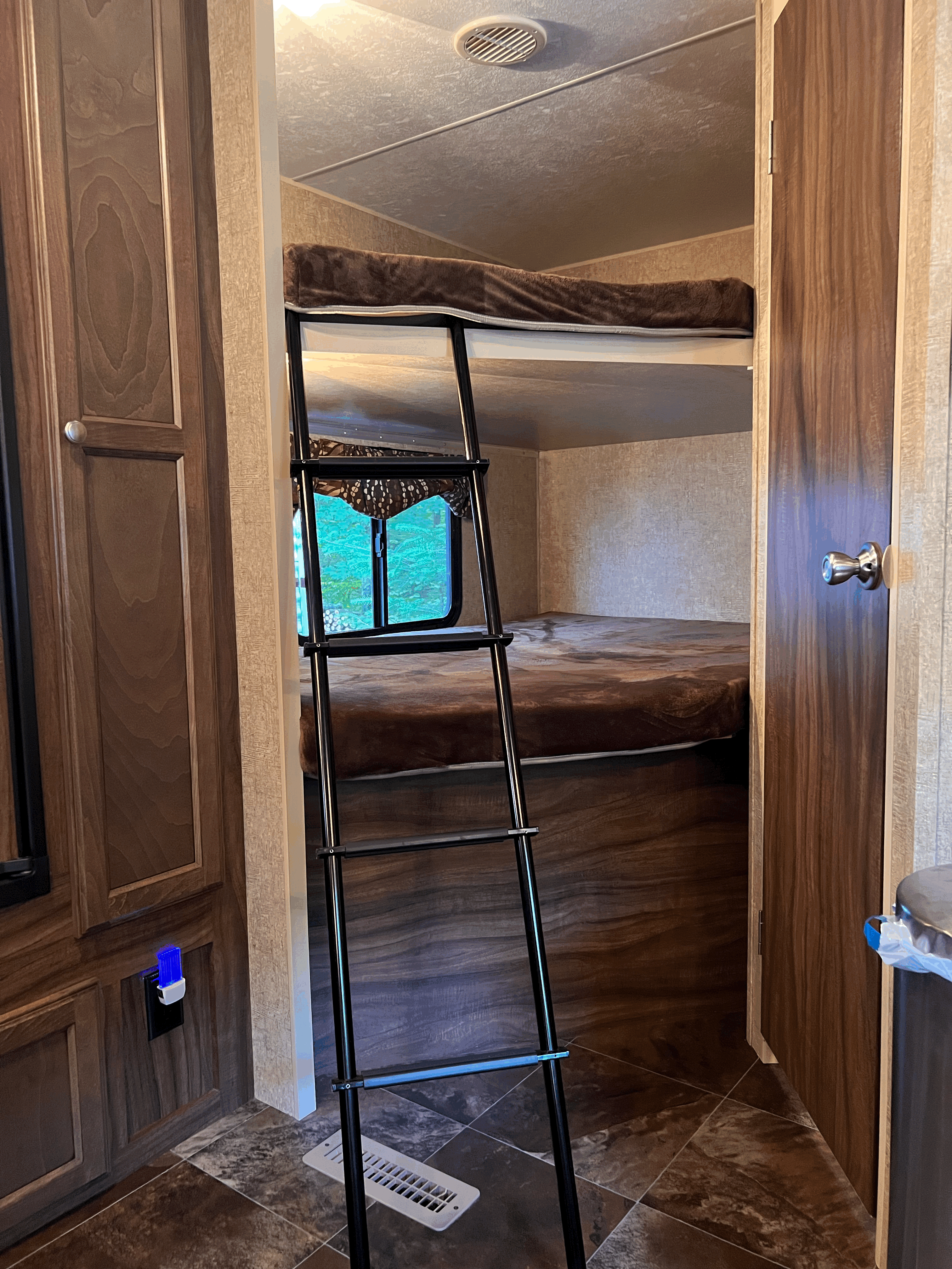 RV rental: A cozy interior featuring bunk beds with a black access ladder, wood-look cabinetry, and tile flooring. Green outdoor view visible.. Sportsmen Show Stopper 2015