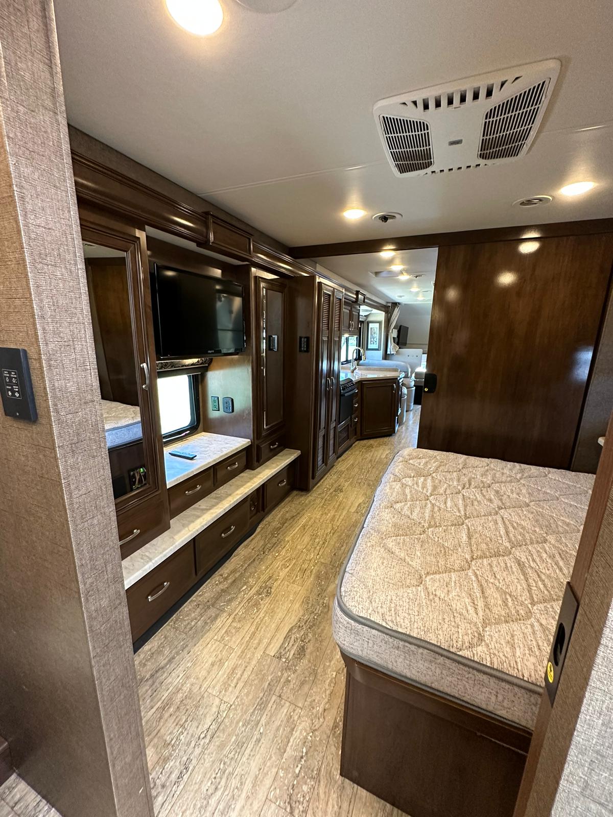 Spacious RV rental interior showcasing a bed, galley kitchen, and bunk/living area with TV, ready for travel.. Thor Four Winds 2017