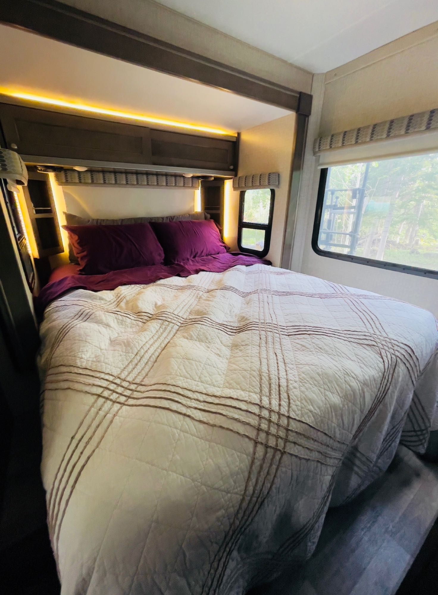 Experience cozy nights in this comfortable RV rental bedroom, featuring warm ambient lighting and plush bedding.. Winnebago Ford Transit Winnebago Fuse 23T Motorhome 2018