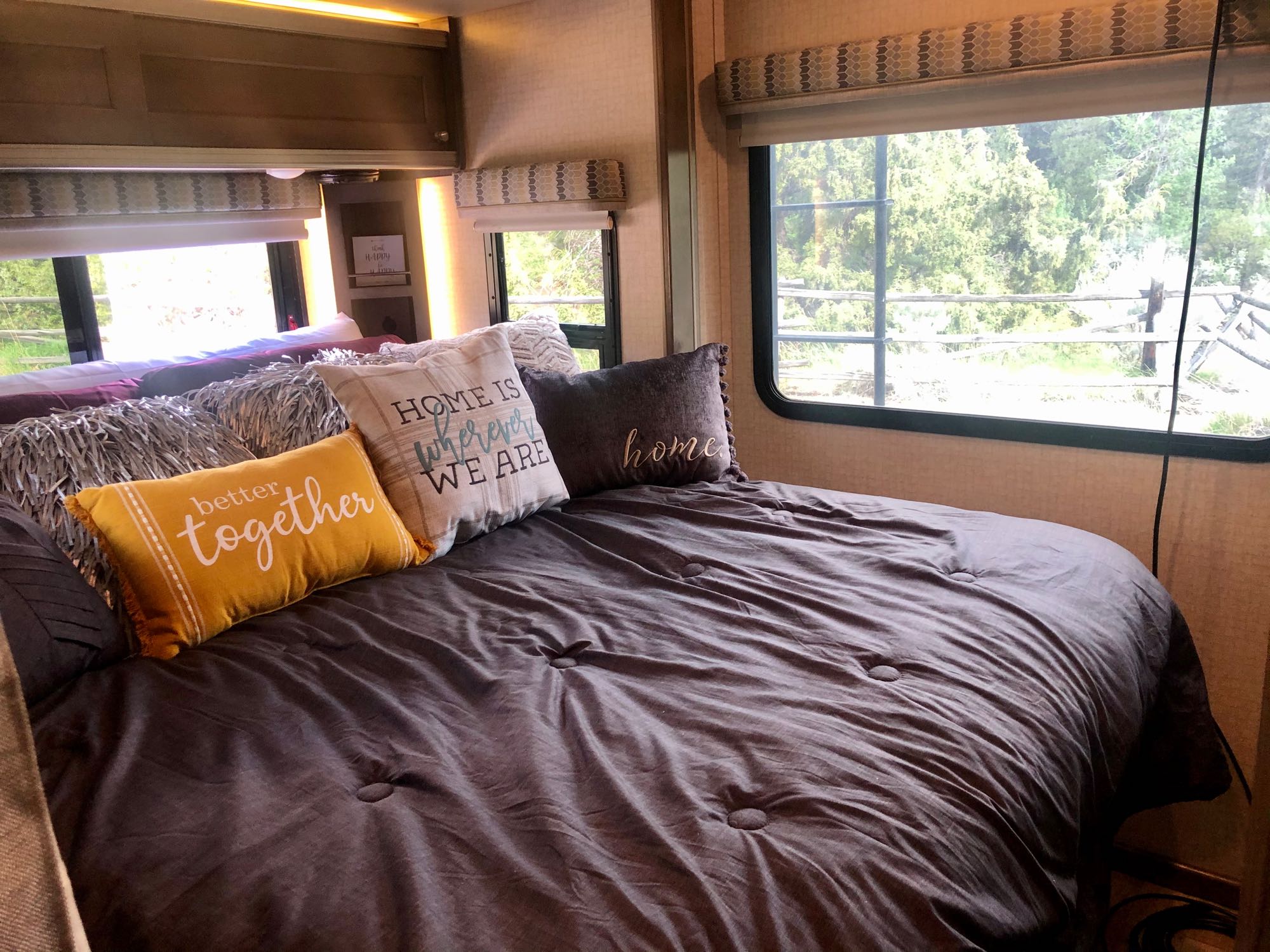 Cozy RV rental bedroom with decorative pillows and nature views, offering a comfortable home away from home for travel.. Winnebago Ford Transit Winnebago Fuse 23T Motorhome 2018