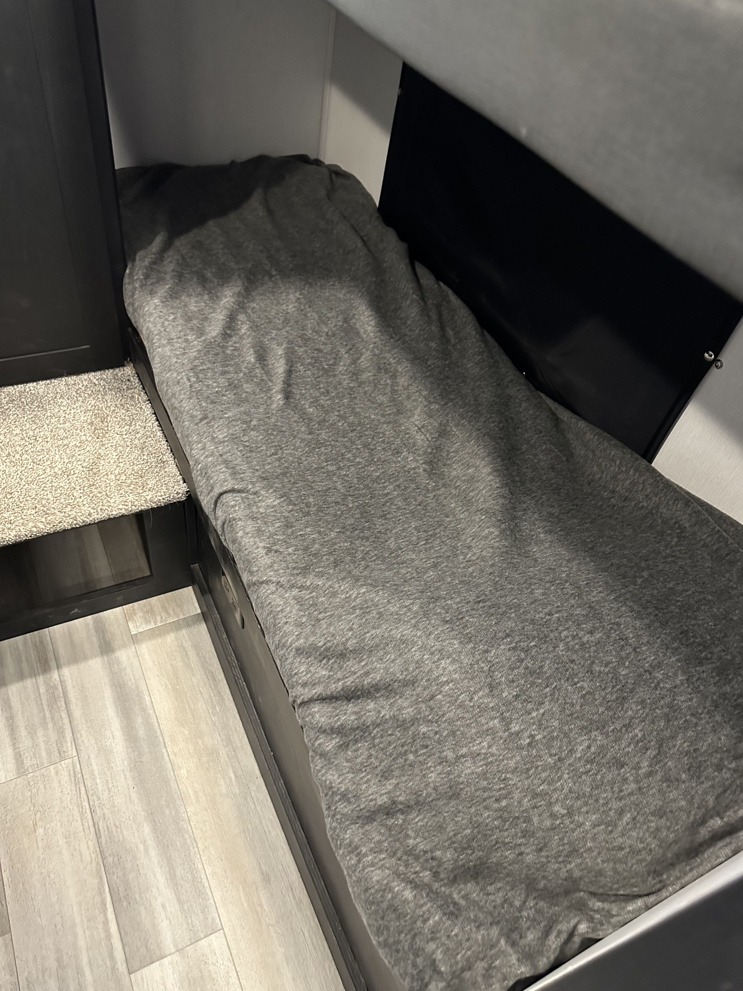 Cozy grey bunk bed in an RV rental, featuring a carpeted step and wood-look floor.. Forest River Coachmen Freedom Express Ultra Lite 2022