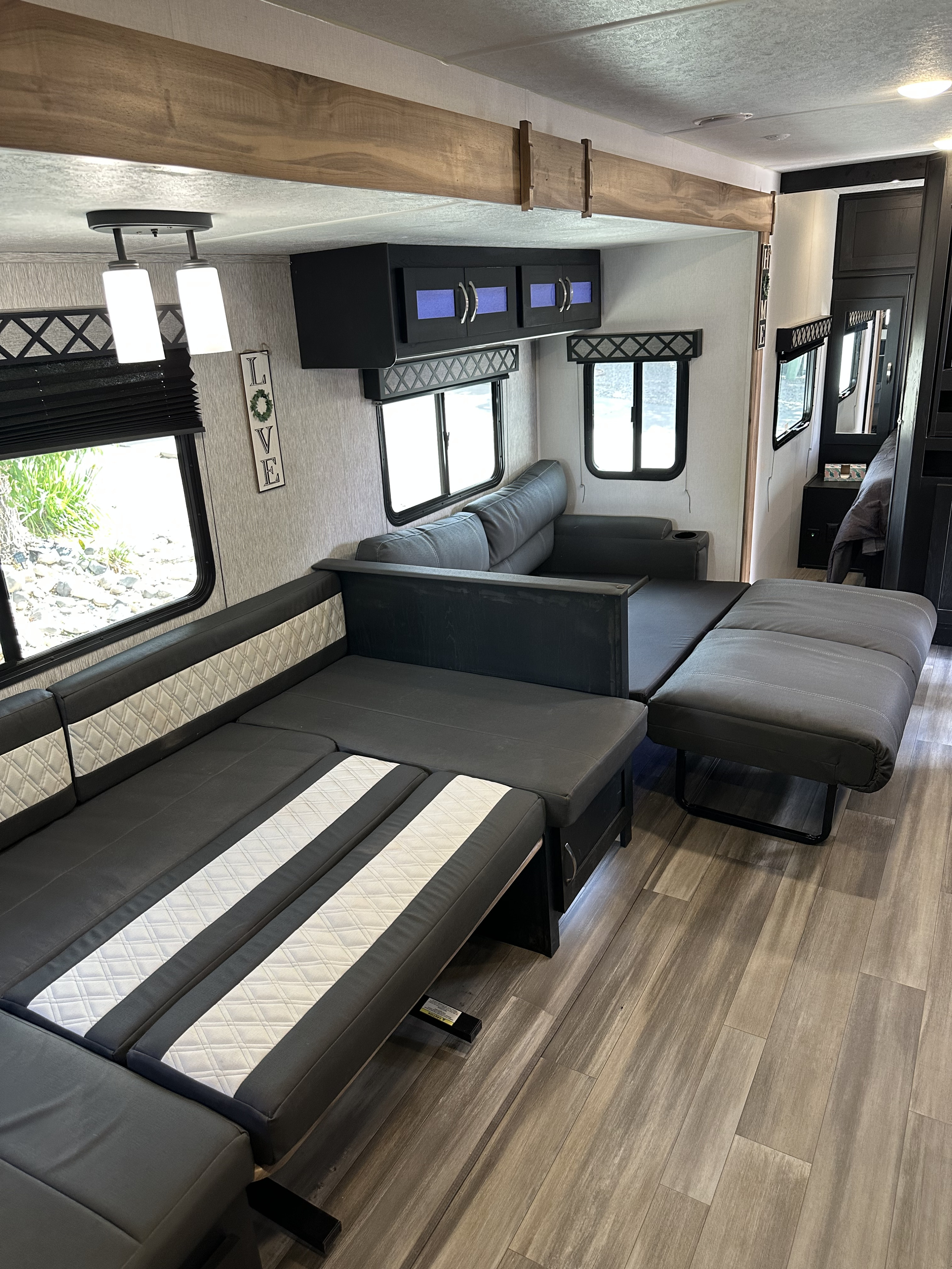 Spacious, modern RV rental interior with modular sofa/bed, cabinets, and wood accents. Ready for comfortable travel!. Forest River Coachmen Freedom Express Ultra Lite 2022