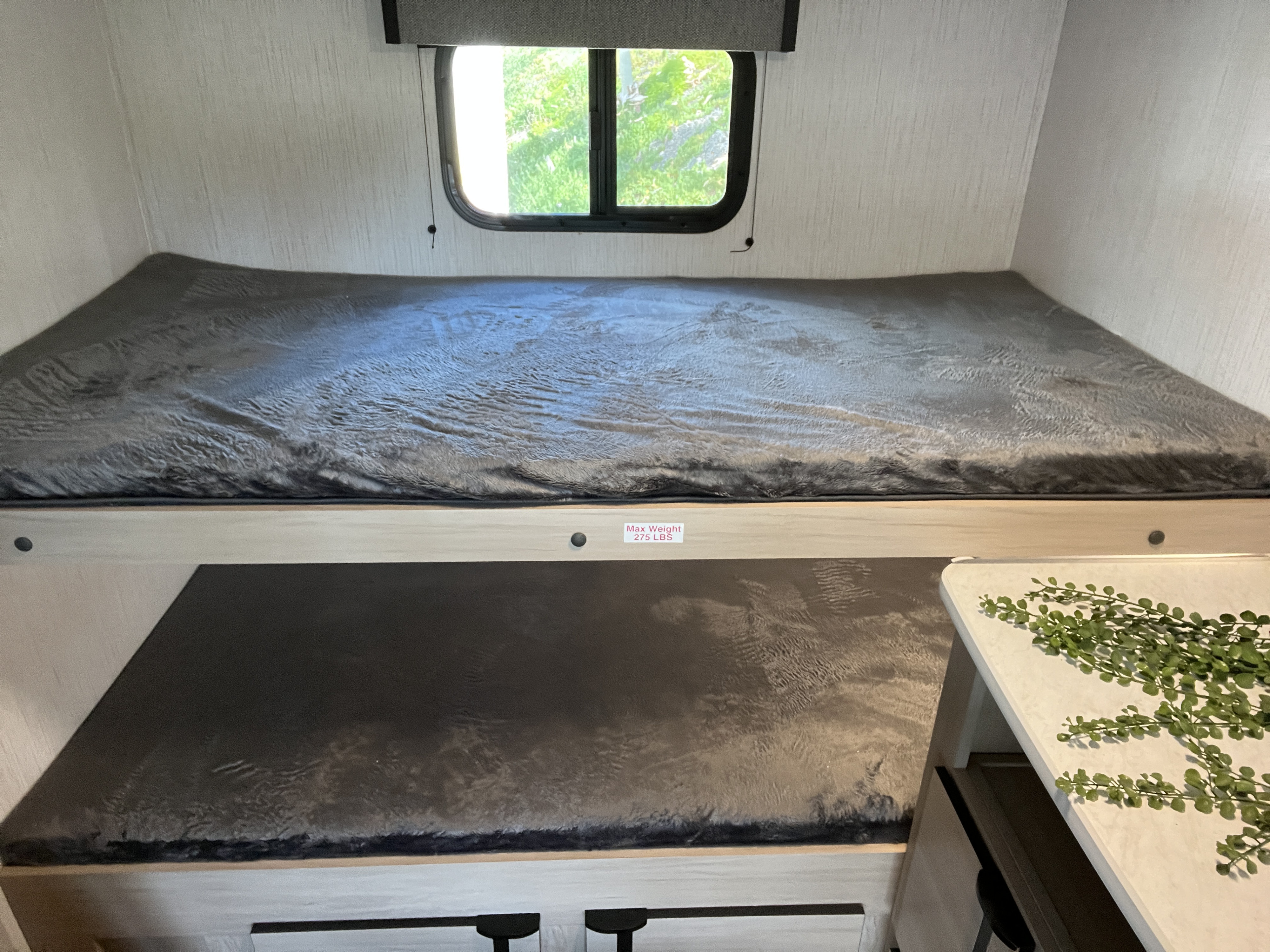 Cozy RV rental bunk beds, with a window and 275 LBS weight limit on the top bunk, offering a compact sleep area.. Heartland RVs 28qd 2023