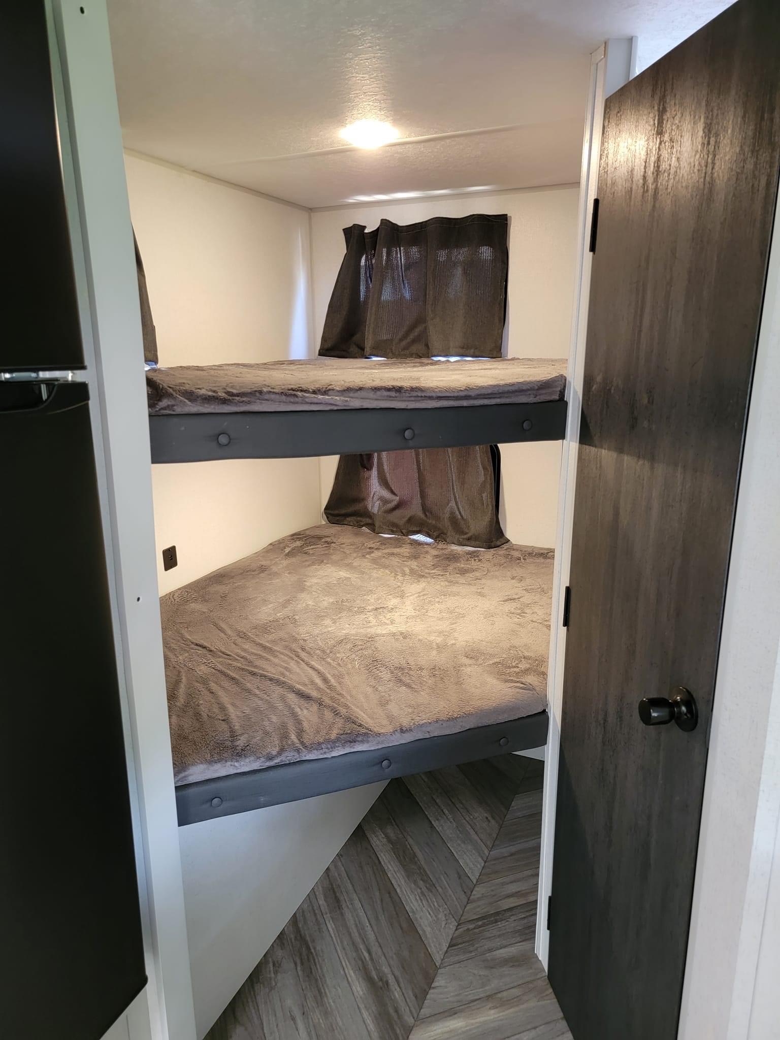 RV rental bunkhouse: Two cozy beds with blankets & curtains, built-in light, and wood-look flooring. Ideal for travel.. Forest River Salem FSX 2022